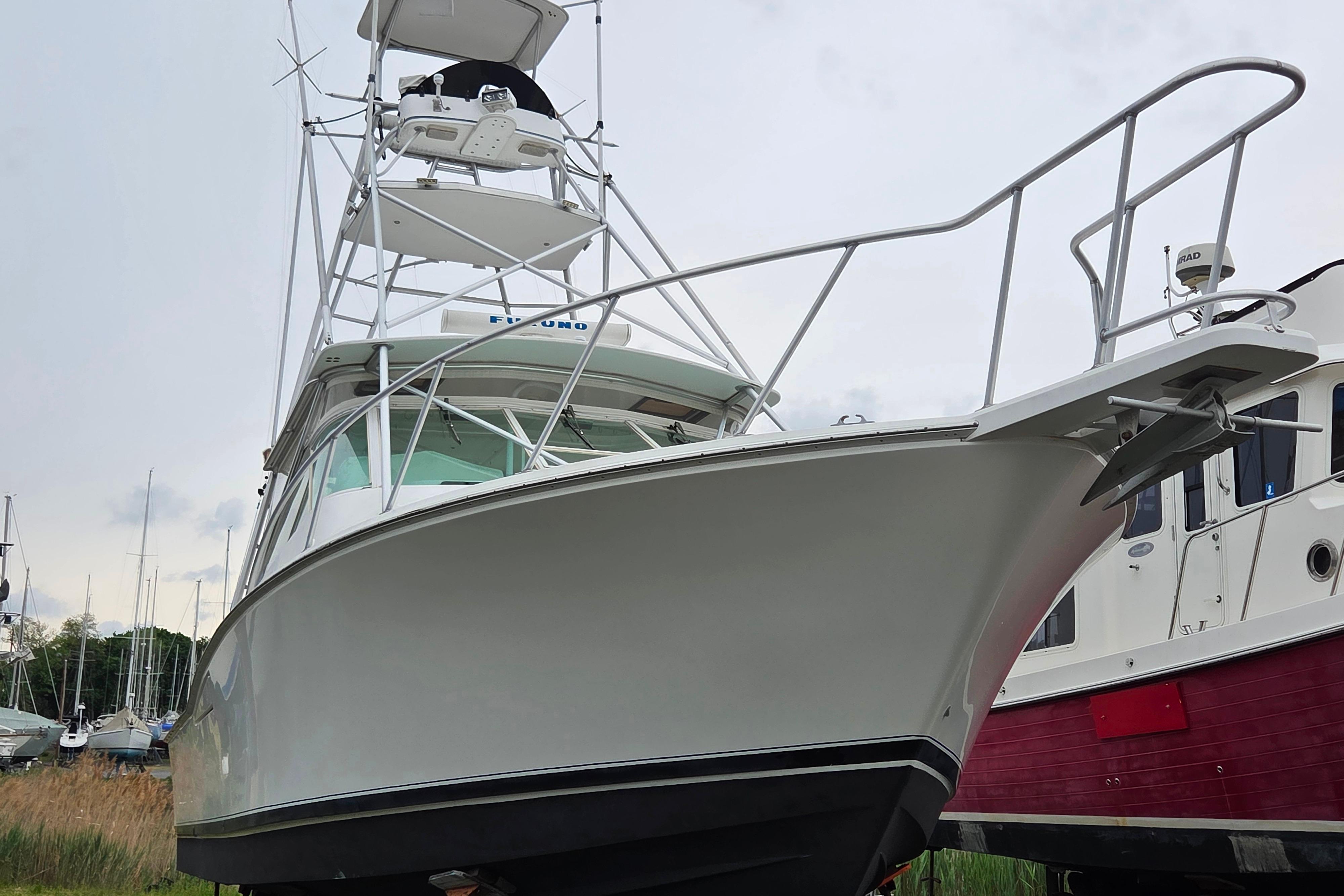 1999 Cabo 35 Express boat with tower, docked alongside other vessels.