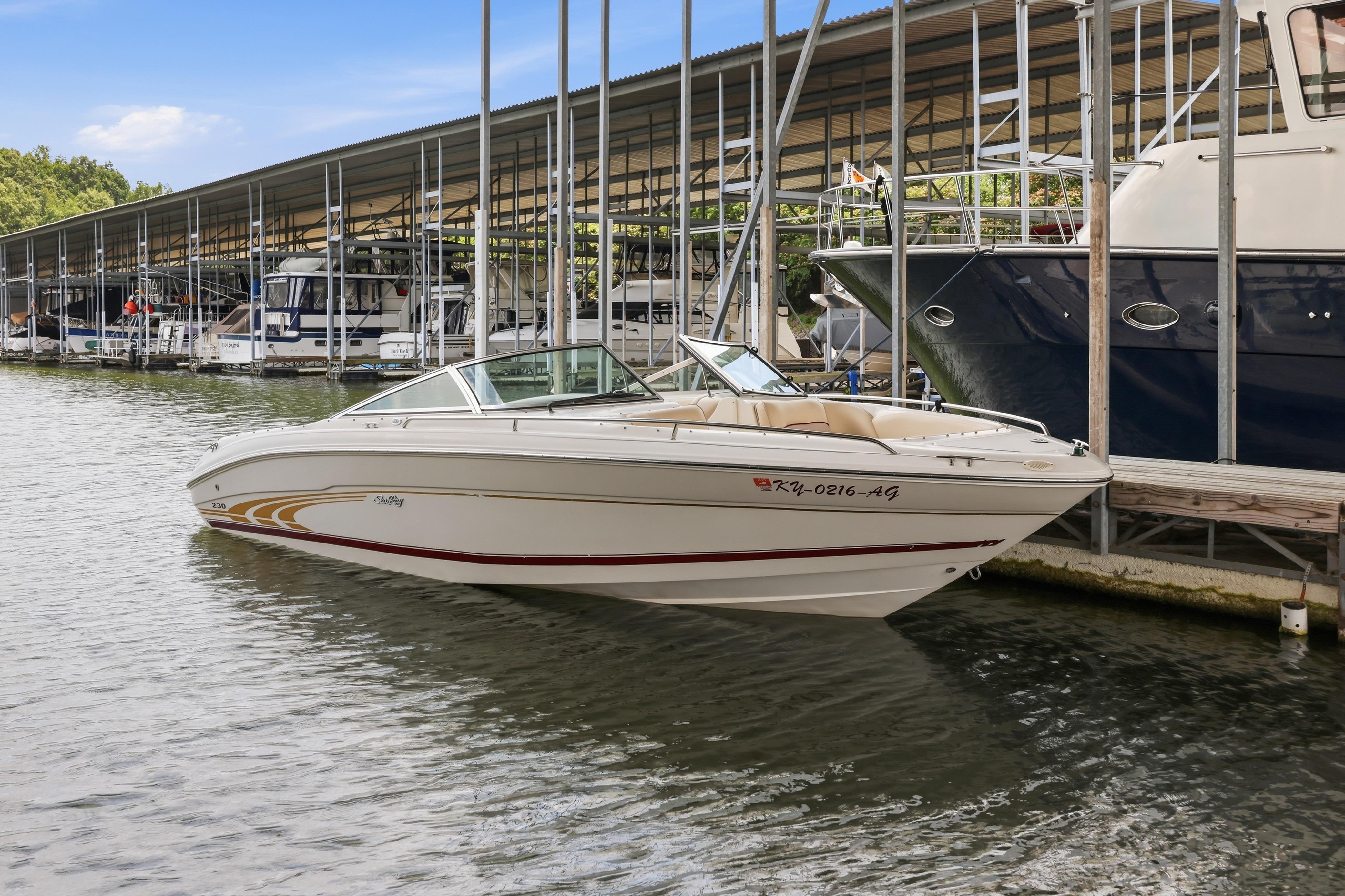 1997 Sea Ray 230 Signature boat docked at marina under covered shelter.