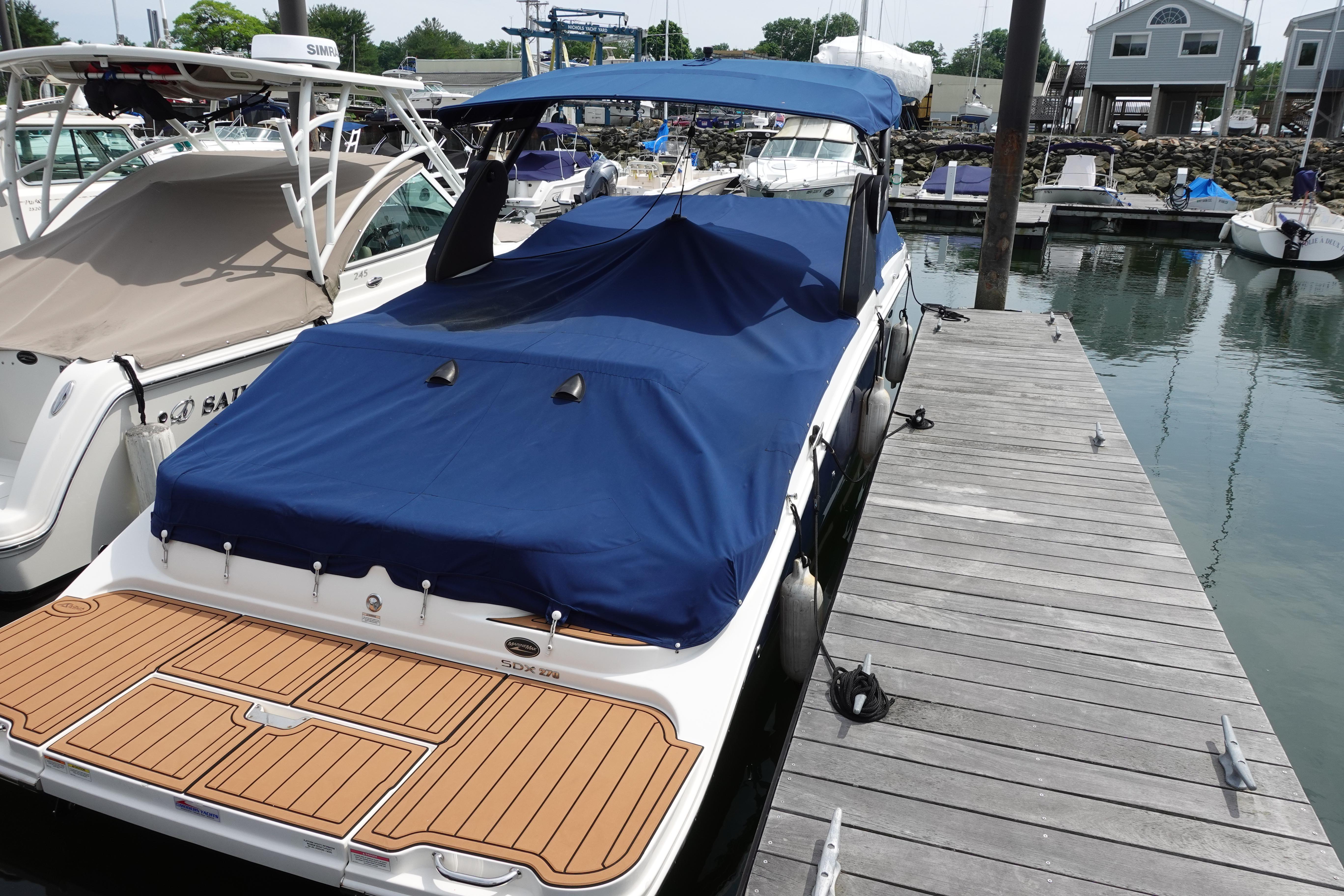 2018 Sea Ray SDX 270 boat docked with blue cover and wooden deck.