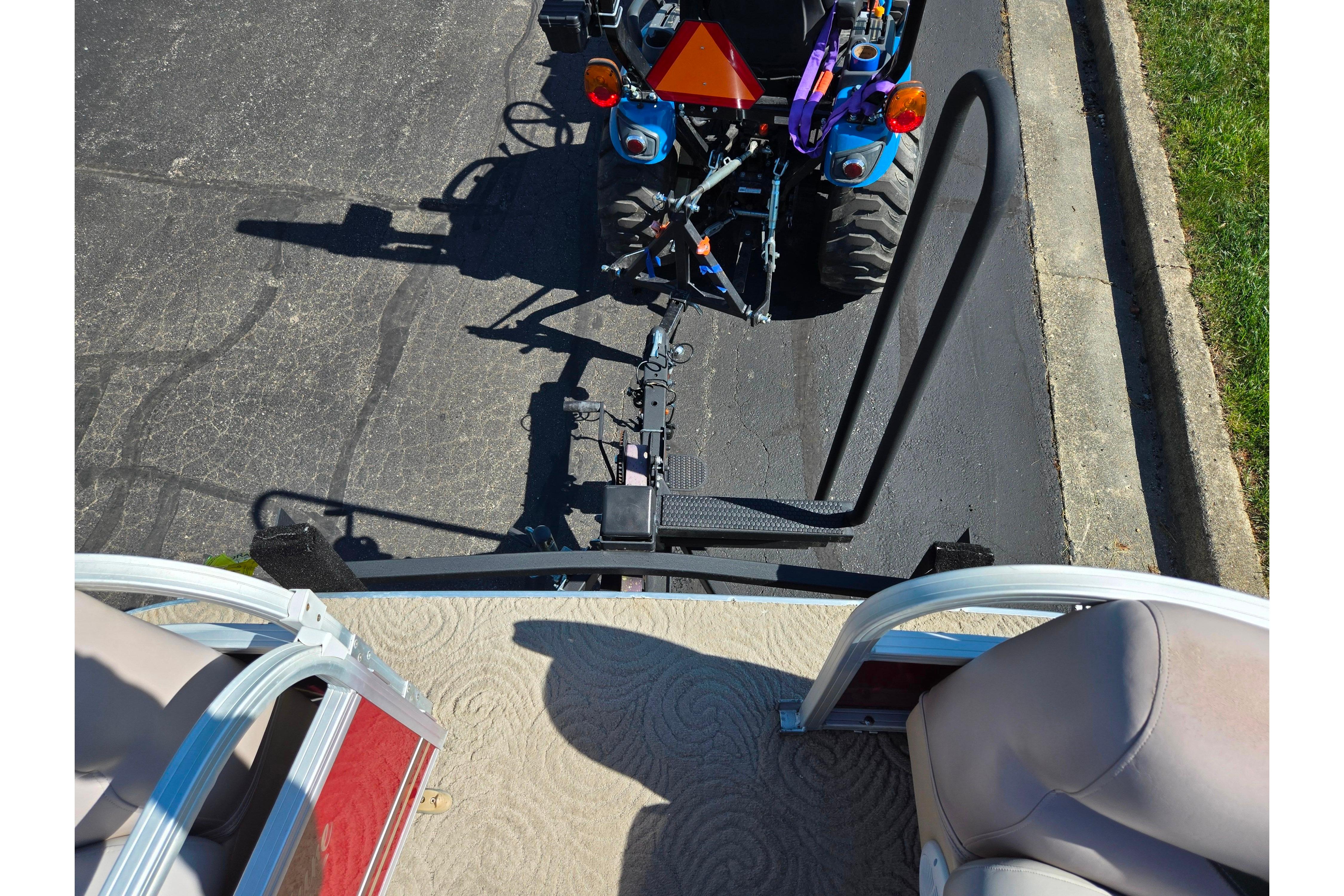 2014 Sun Tracker Party Barge 20 DLX hitched to a blue tractor on pavement.