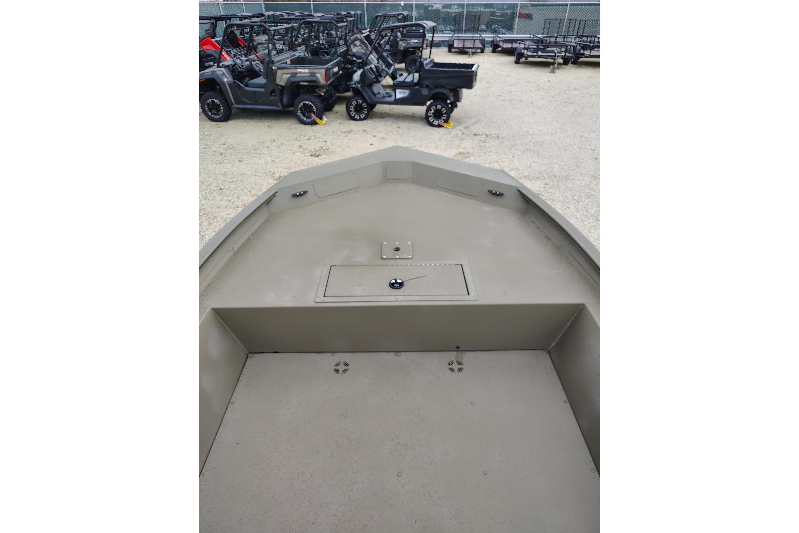 2025 Tracker Grizzly 1860 Utility boat interior with storage compartment, parked near off-road vehicles.