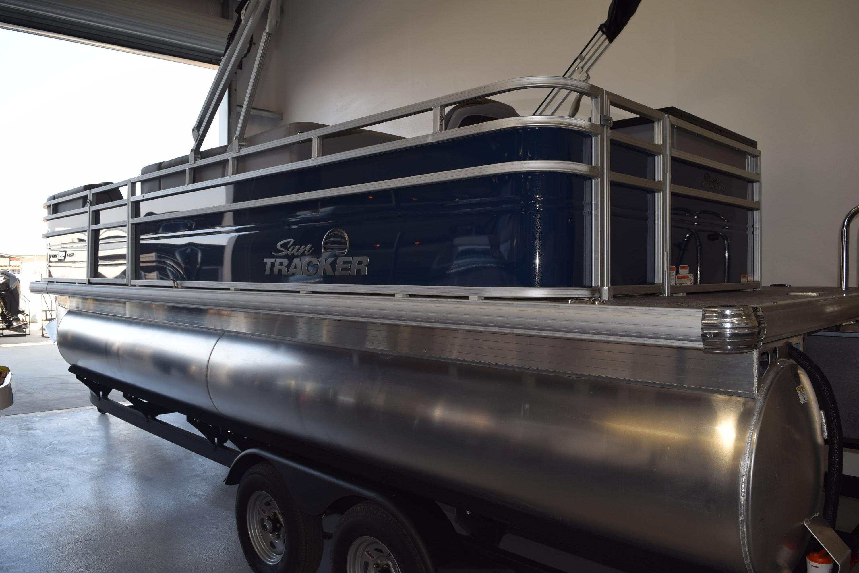 2026 Sun Tracker SportFish 22 DLX pontoon boat in a garage setting.
