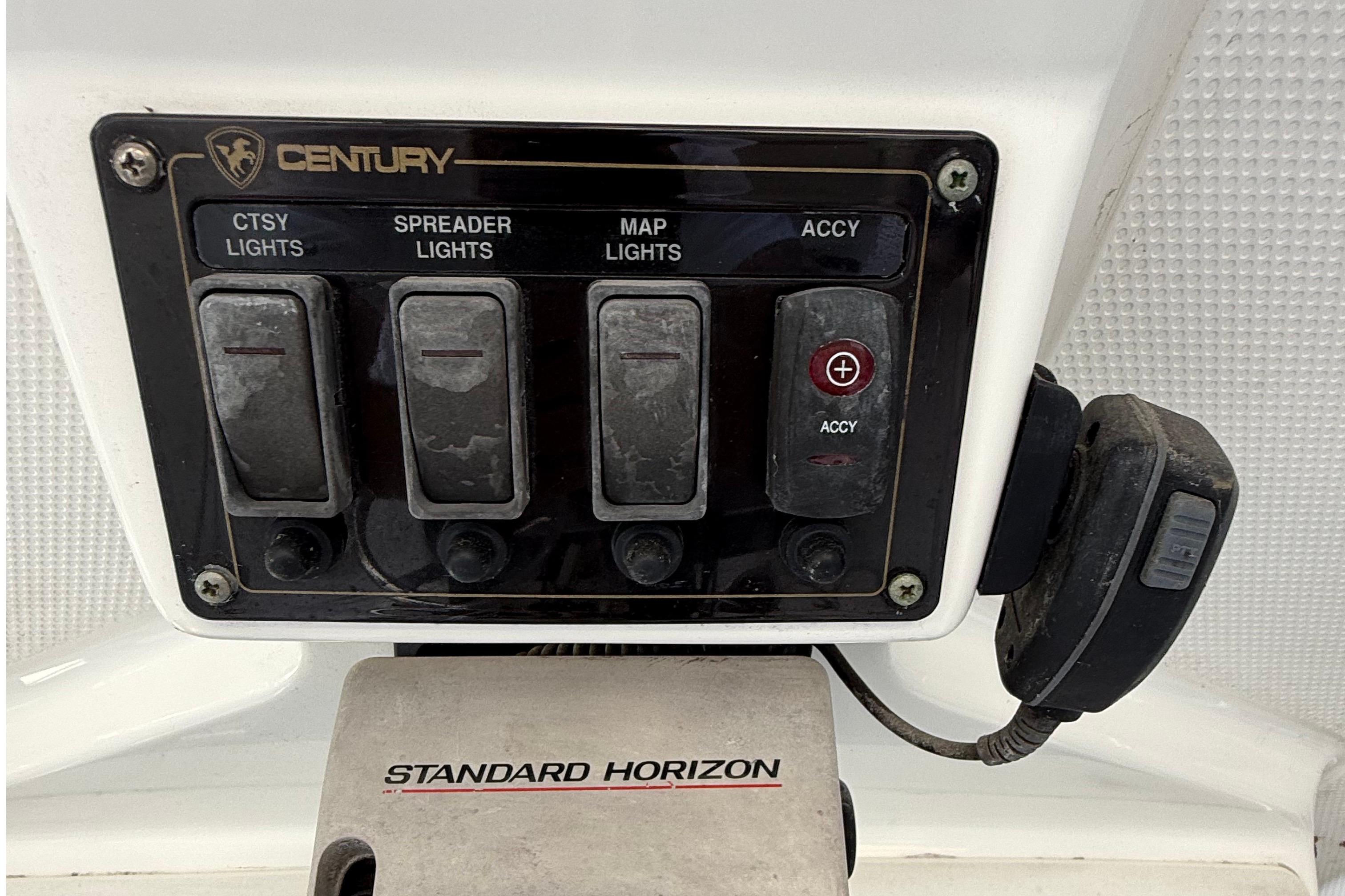 Control panel of a 2008 Century 2901 Center Console boat with light switches and radio.