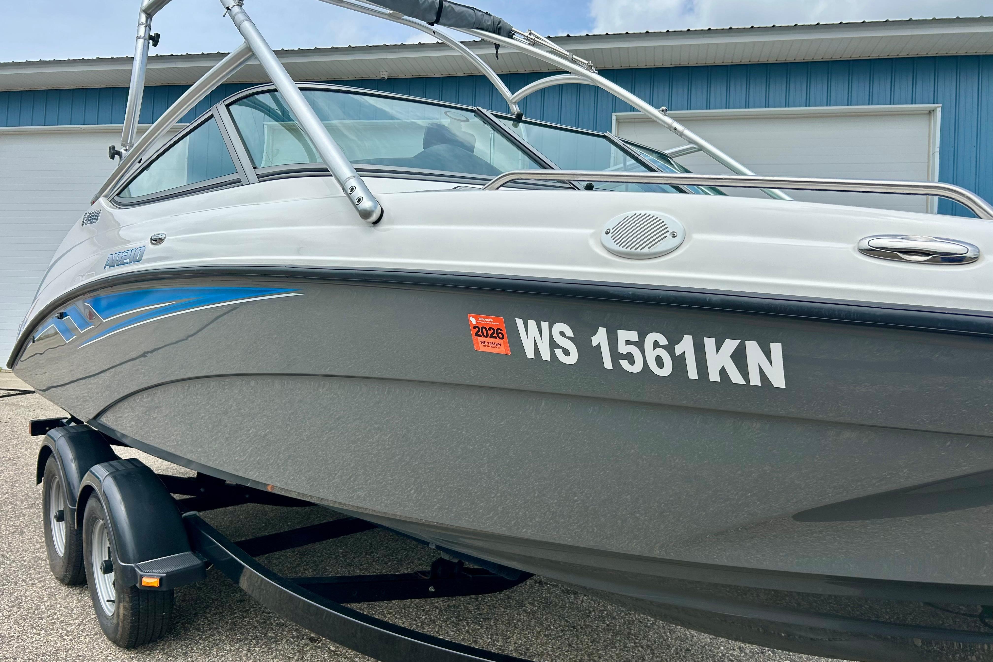 2015 Yamaha Boats AR210 on trailer, gray hull, registration WS 1561KN, parked near blue building.