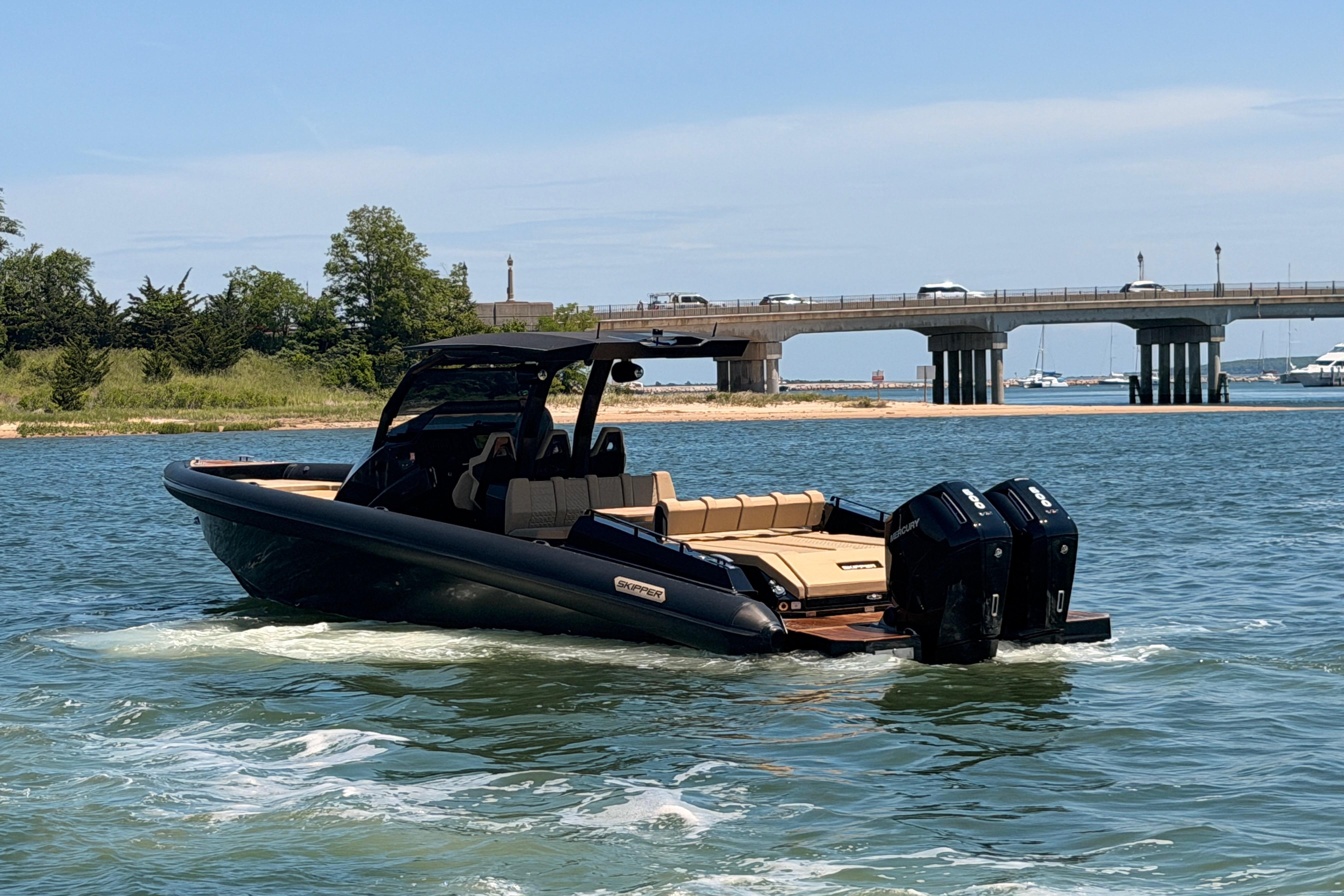 2023 Skipper-BSK 42NC boat cruising near a bridge on a sunny day.