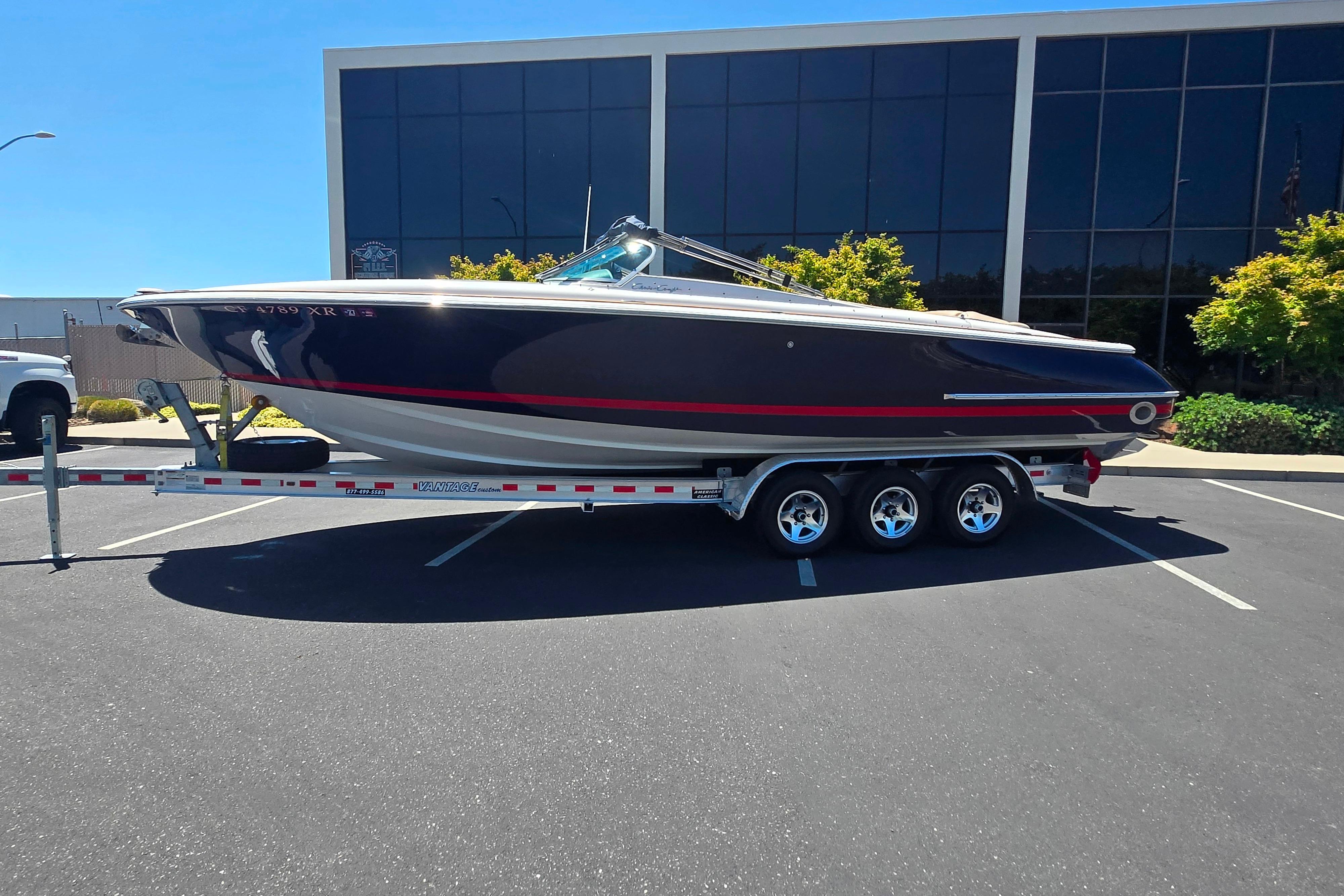 2002 Chris-Craft Launch 28 GT I/O boat on trailer in parking lot.