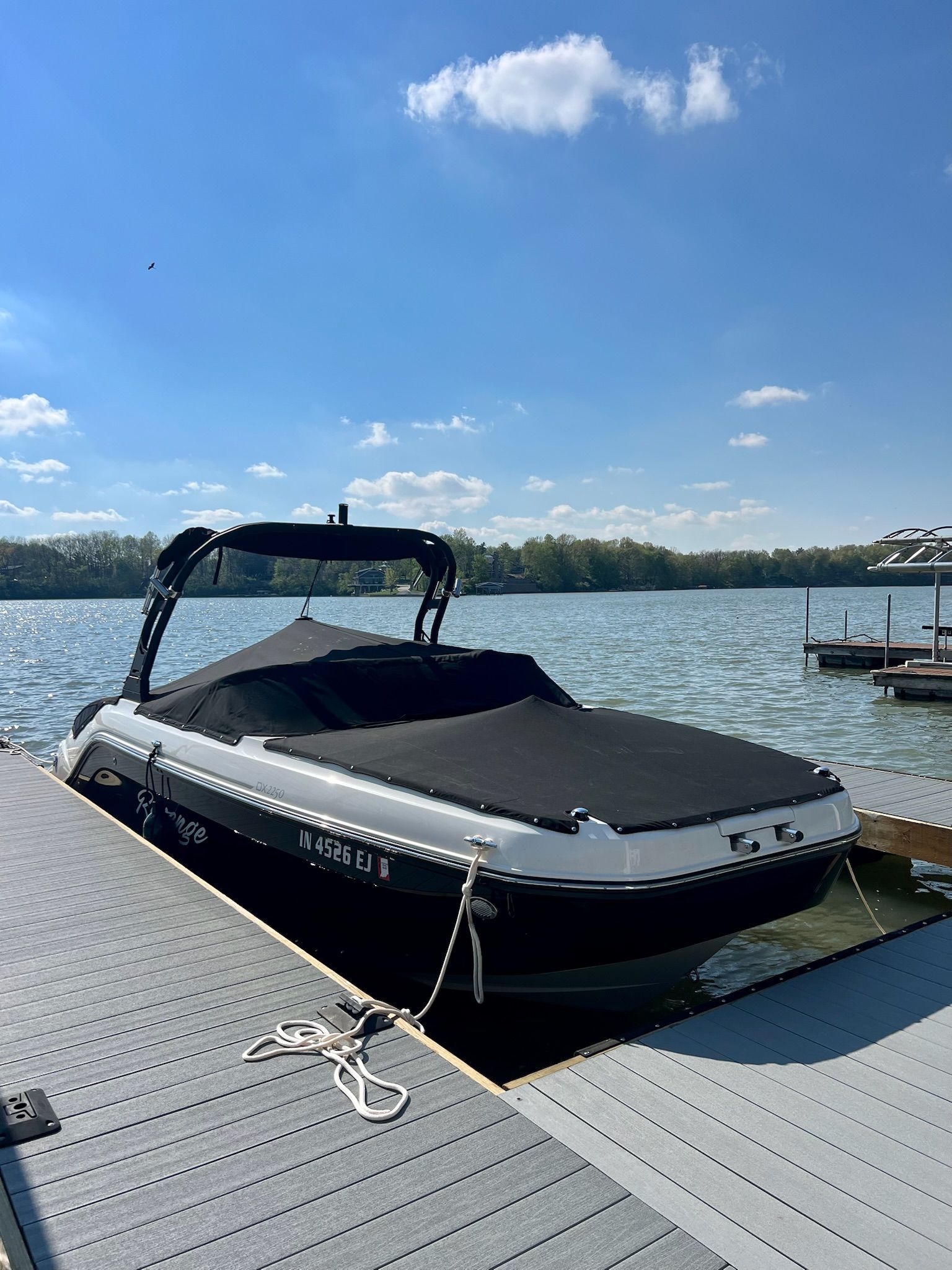 2022 Bayliner DX 2250 boat docked on a sunny lake with clear skies.