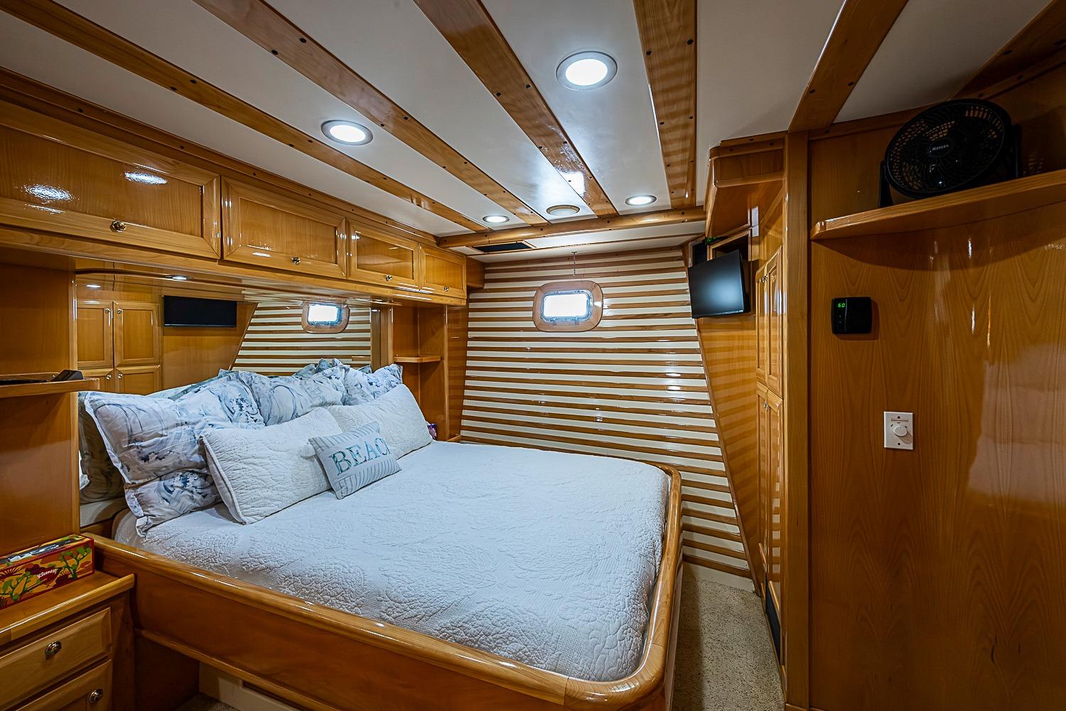 Luxurious cabin interior of 2003 Magna Marine Nova Scotia 47 yacht, featuring wood paneling and cozy bedding.