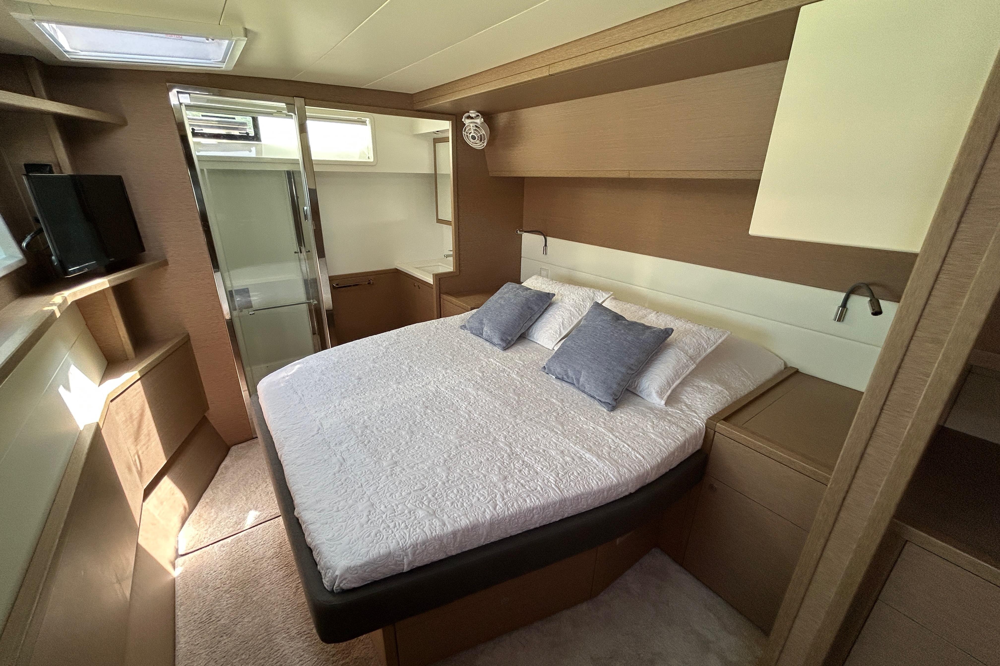 Luxurious bedroom interior of 2021 Lagoon 52 S yacht with modern design and cozy bedding.