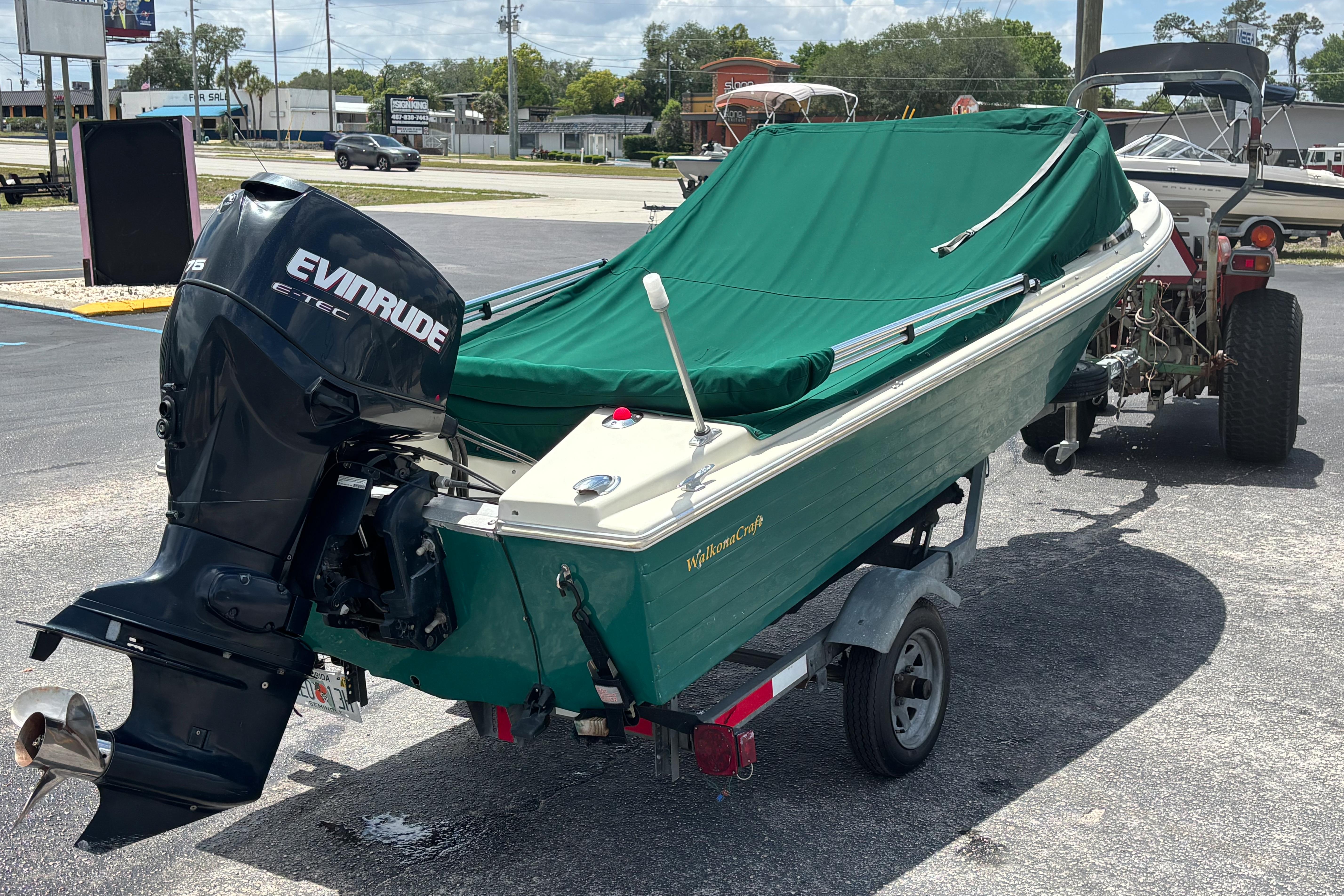 Vintage 1966 Mohawk 15 boat with Evinrude motor, green cover, on trailer.