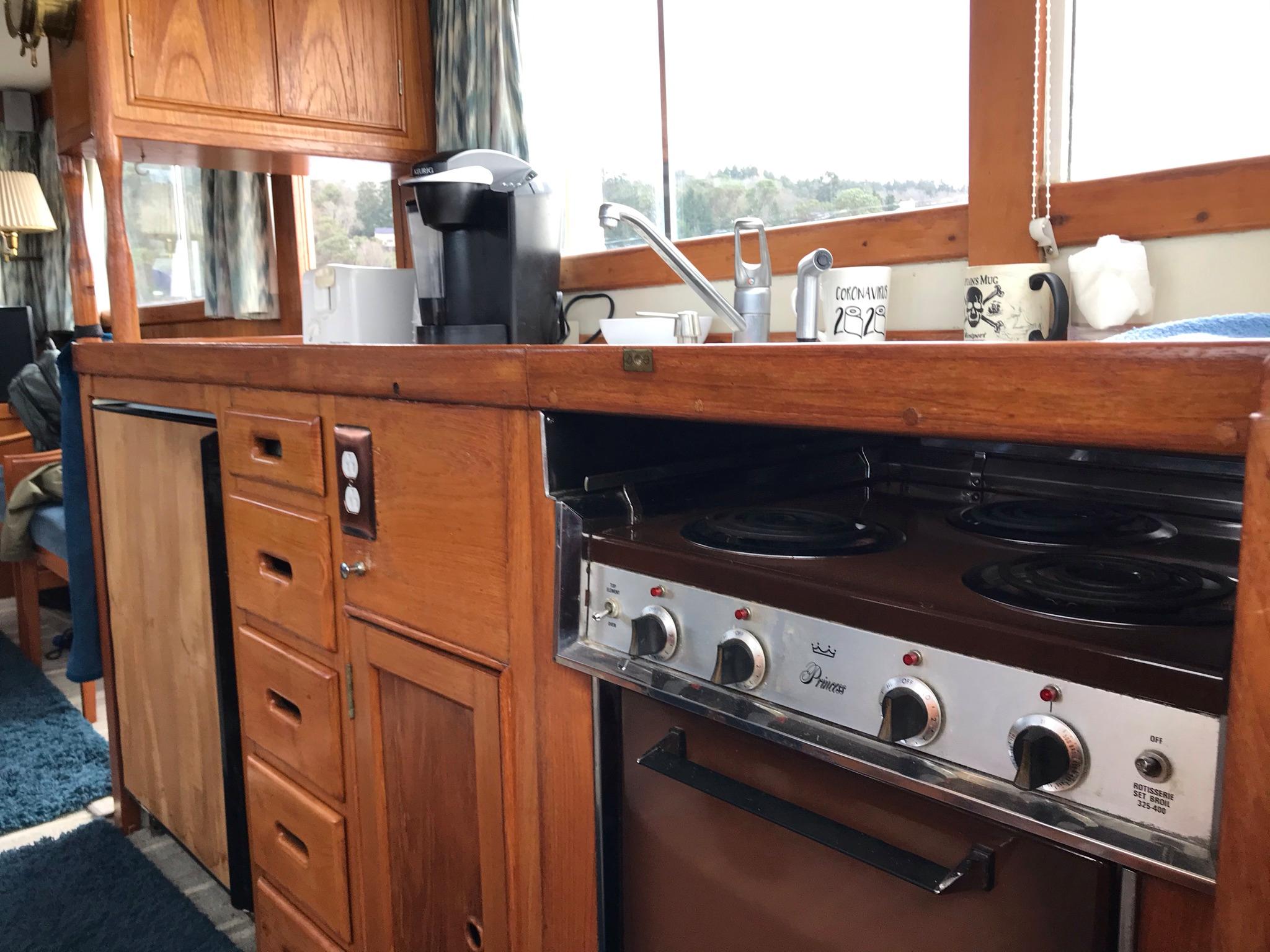 Vintage 1969 Grand Banks 42 Classic yacht kitchen with wooden cabinetry and stove.