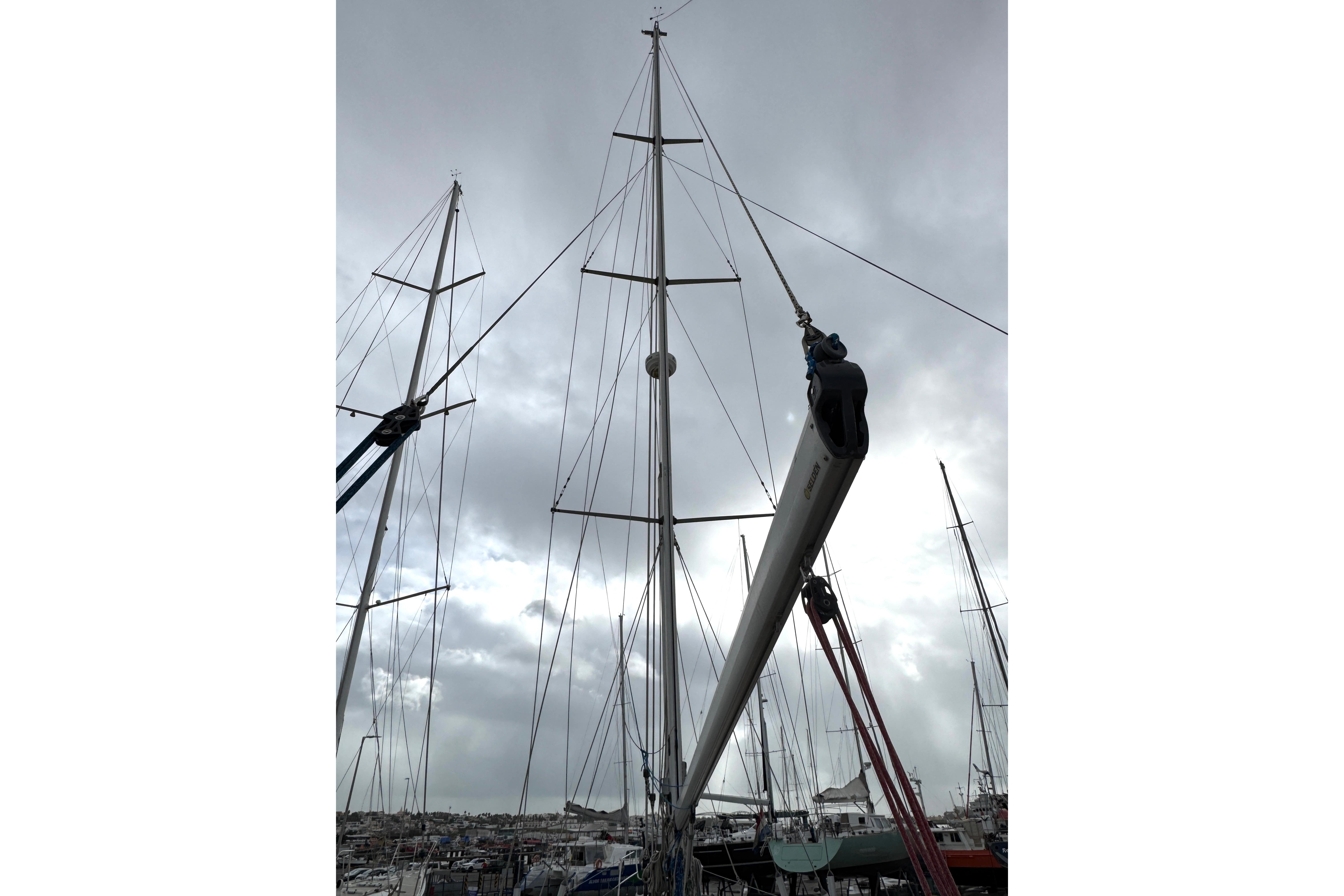 Mast of 2003 Hallberg-Rassy 46 sailboat against cloudy sky in marina.