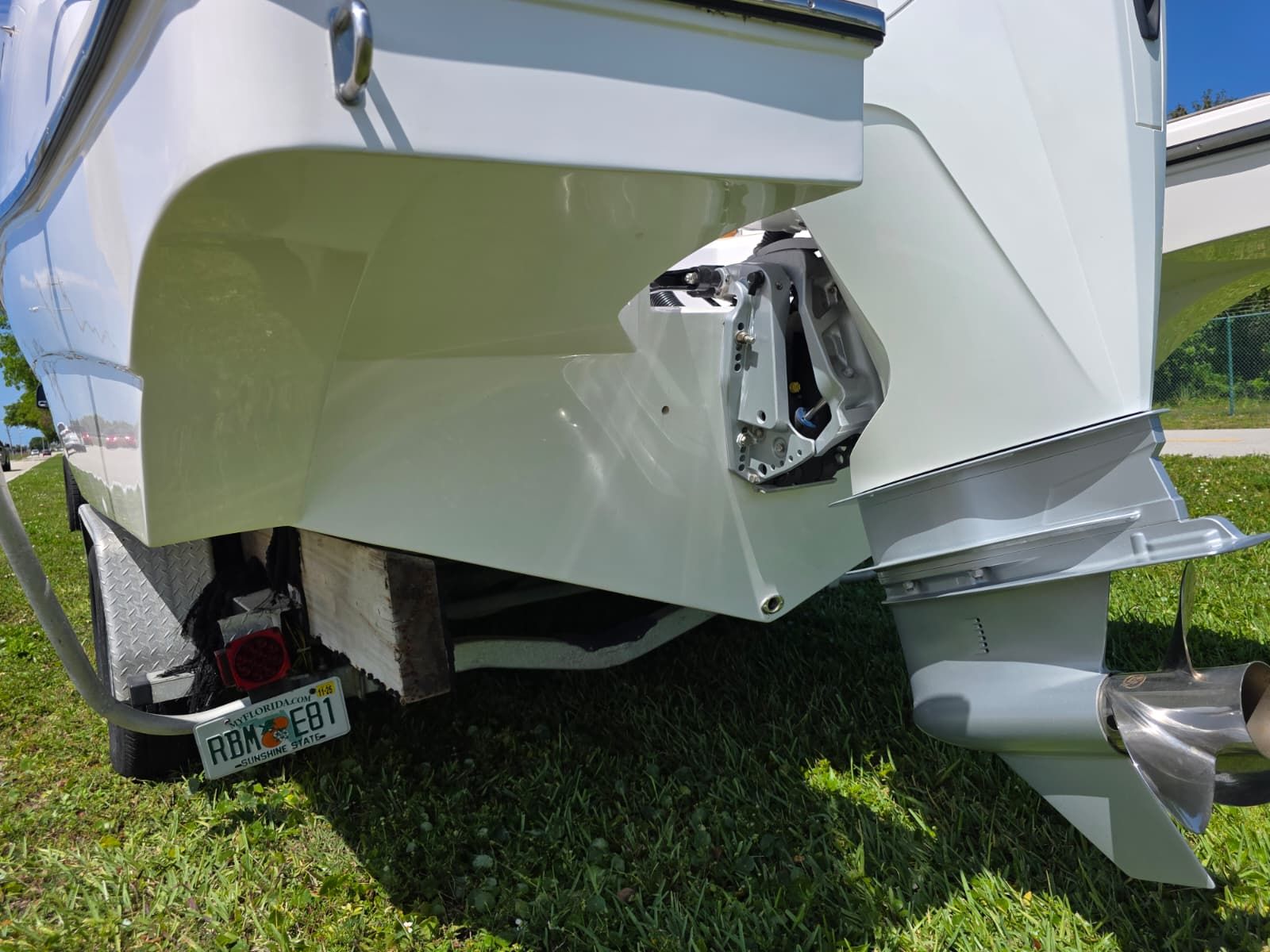 The image shows the stern of a boat with an outboard motor on grass.