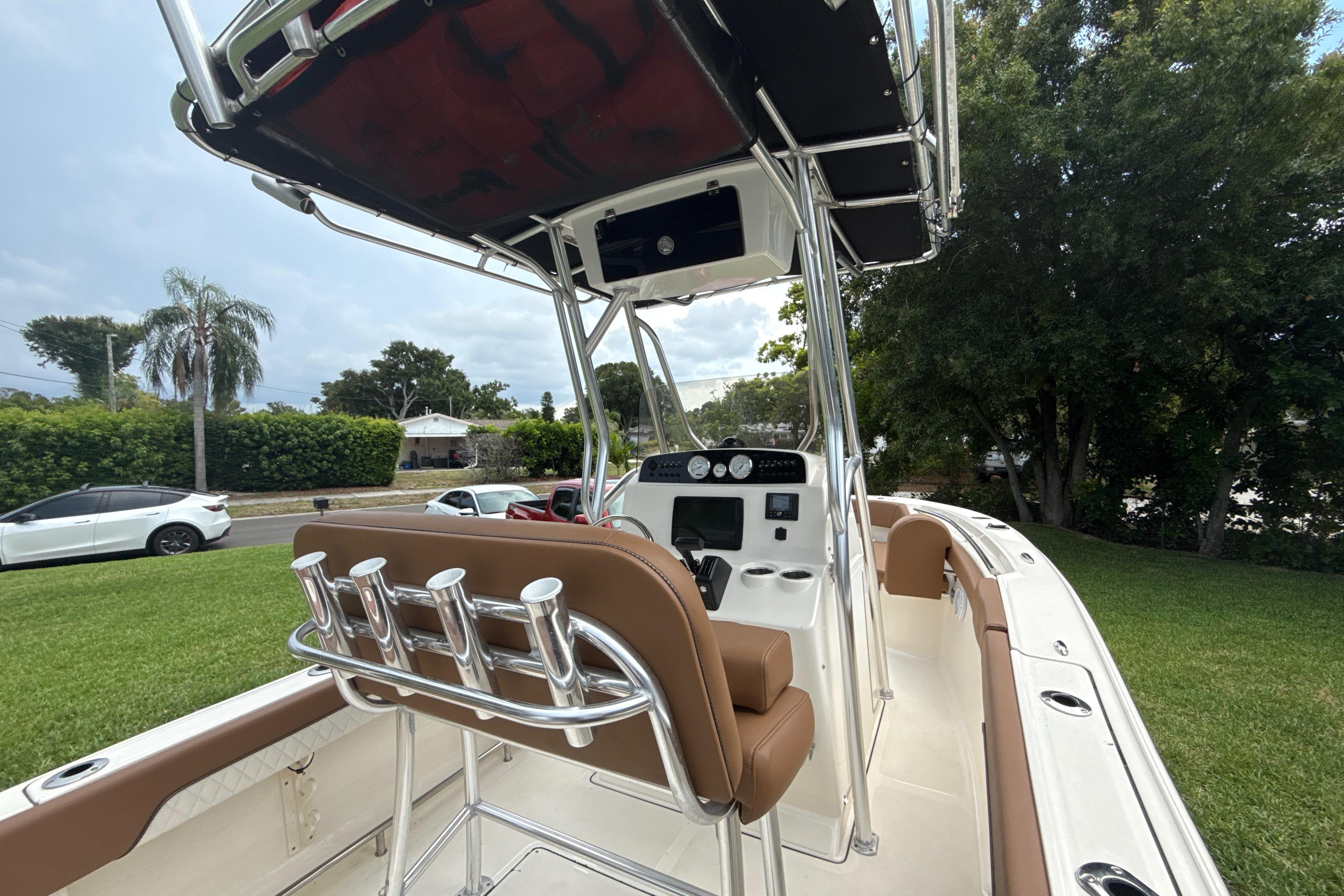 2023 Pioneer 202 Islander boat with brown seating and T-top, parked on grass.