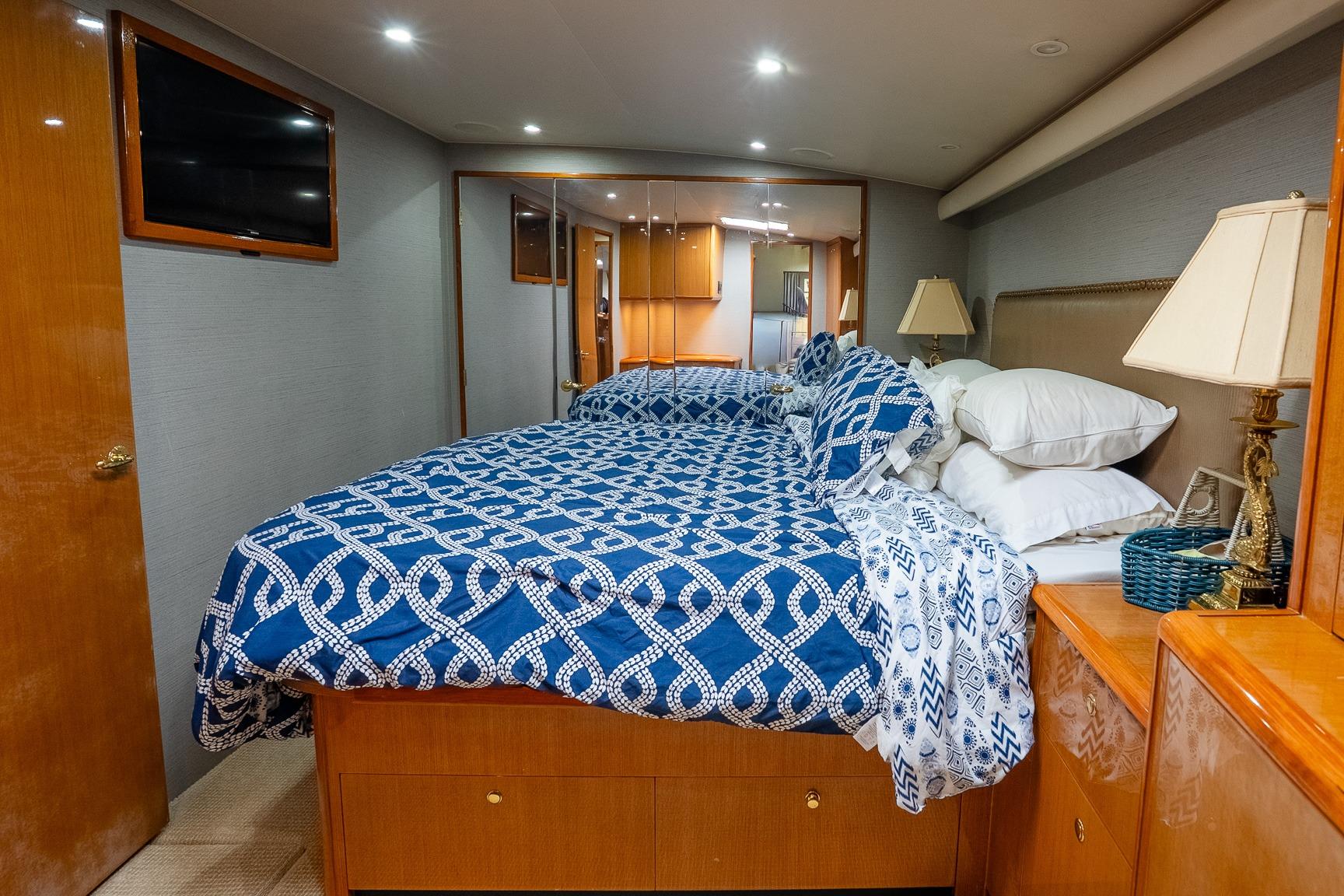 Luxurious bedroom interior of 2002 Viking 61 Enclosed Bridge yacht with blue patterned bedding.