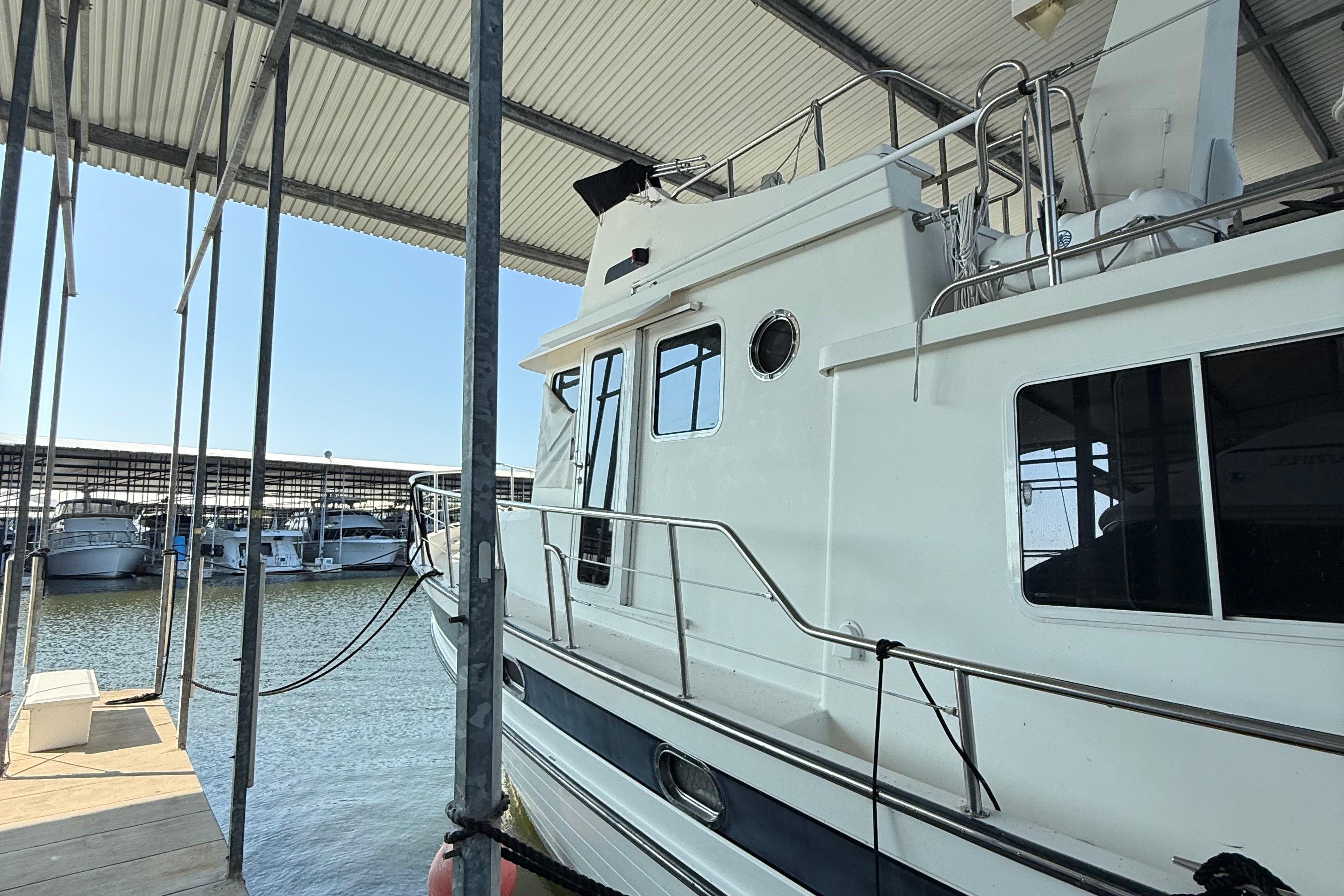 2007 Nordic Tug 54 docked in a marina under a covered shelter.