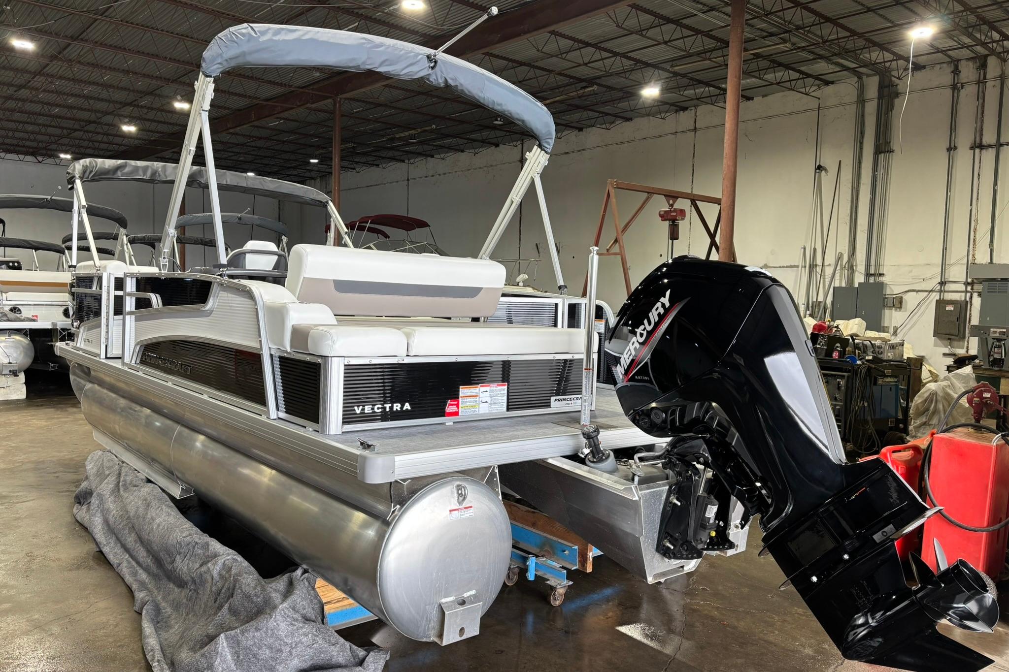 2025 Princecraft Vectra 21 RL pontoon boat with Mercury outboard motor in a warehouse setting.