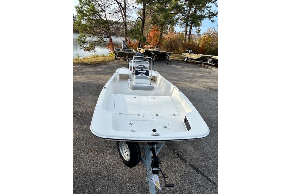 2025 Mako Pro Skiff 17 CC boat on trailer, parked near a lake with trees.