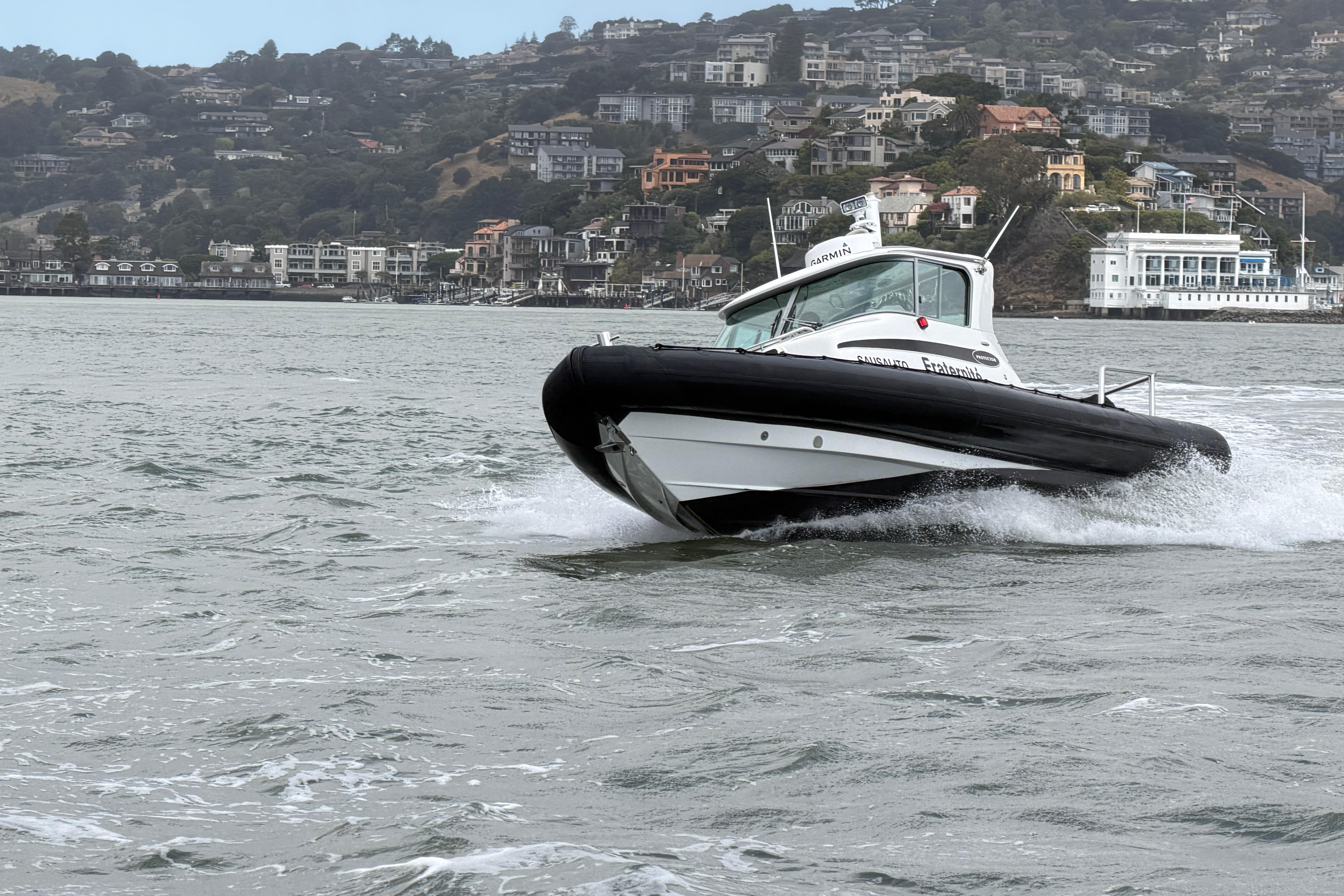2016 Protector Targa 30 boat cruising on water with scenic hillside background.
