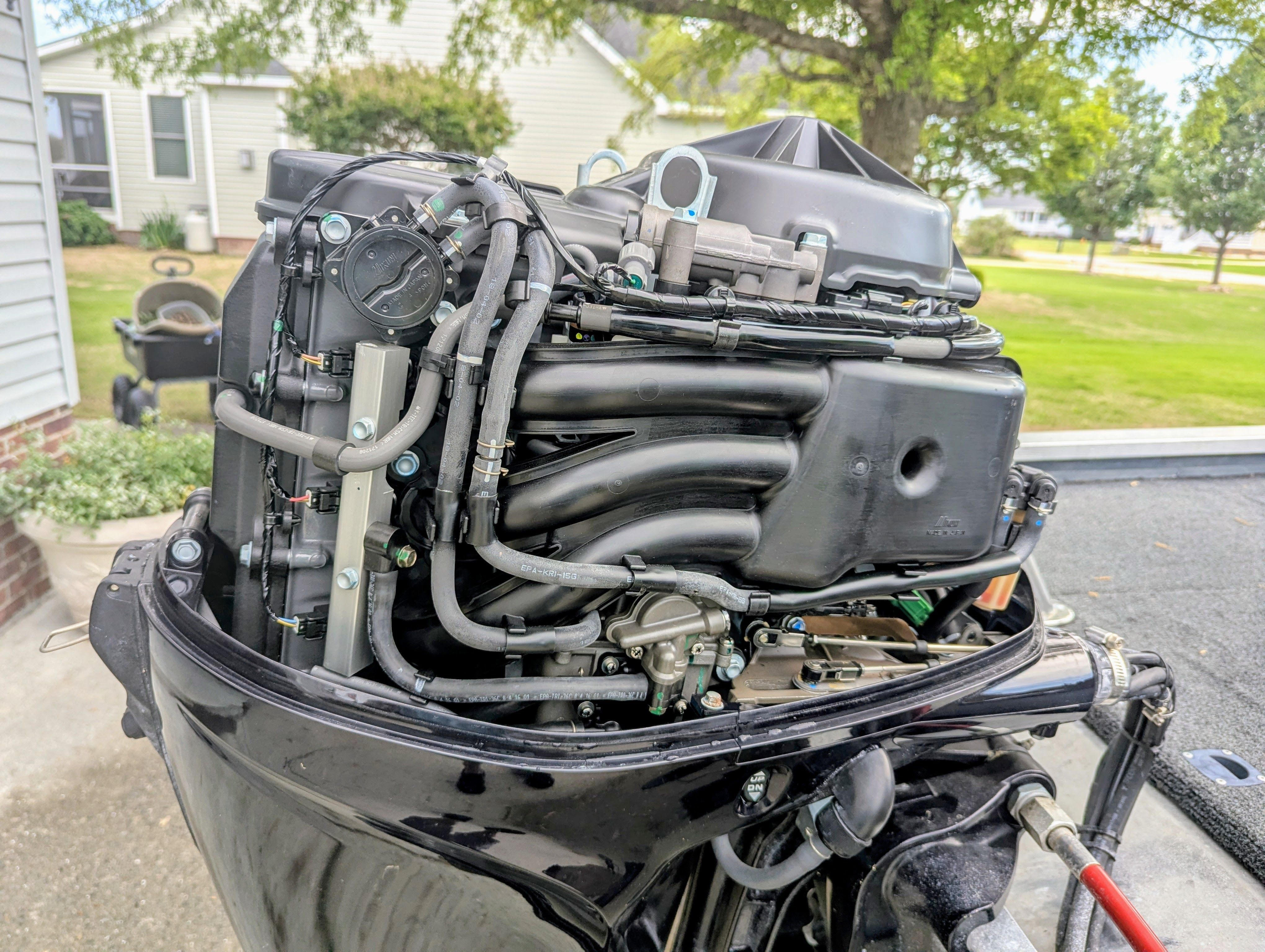Close-up of a boat outboard motor with visible hoses and components.