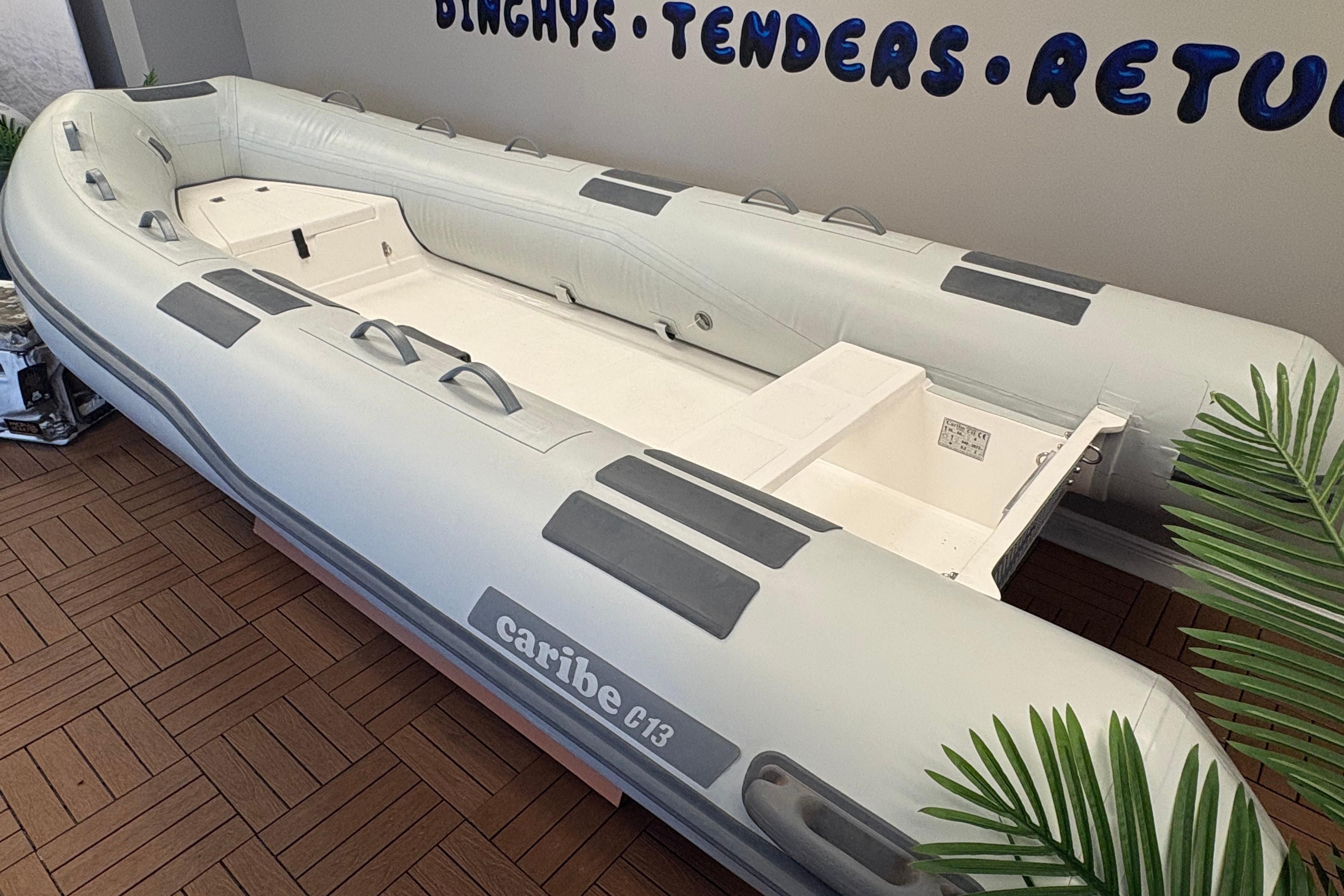 Inflatable Caribe C-13 boat, 2026 model, displayed indoors with wooden flooring.
