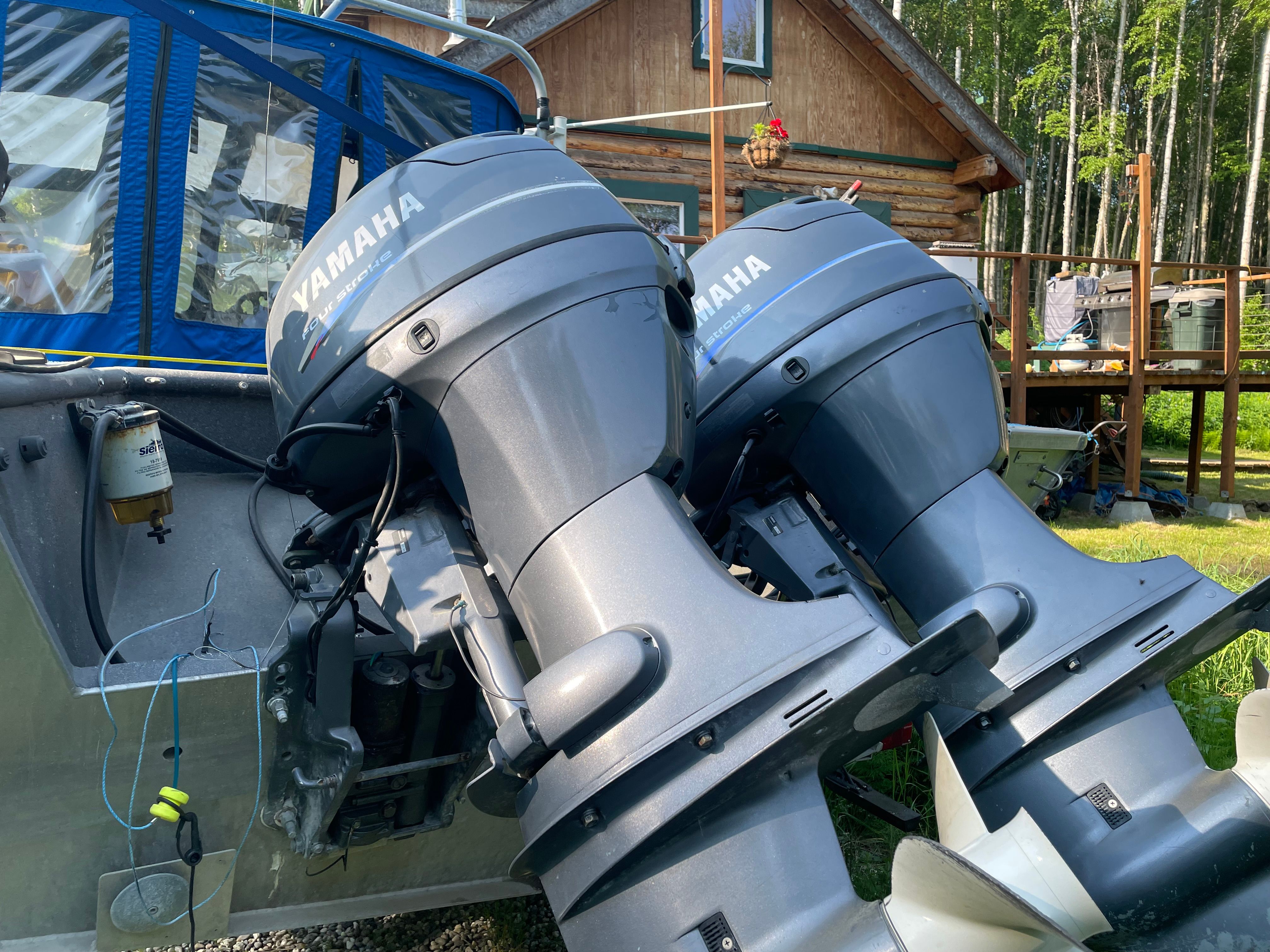 Two Yamaha outboard motors on a boat parked in a wooded area.