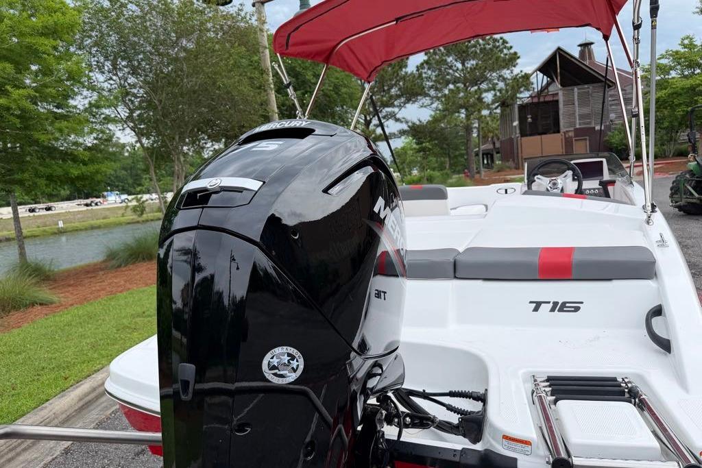 2026 Tahoe T16 boat with Mercury engine and red canopy, parked near a scenic lake.