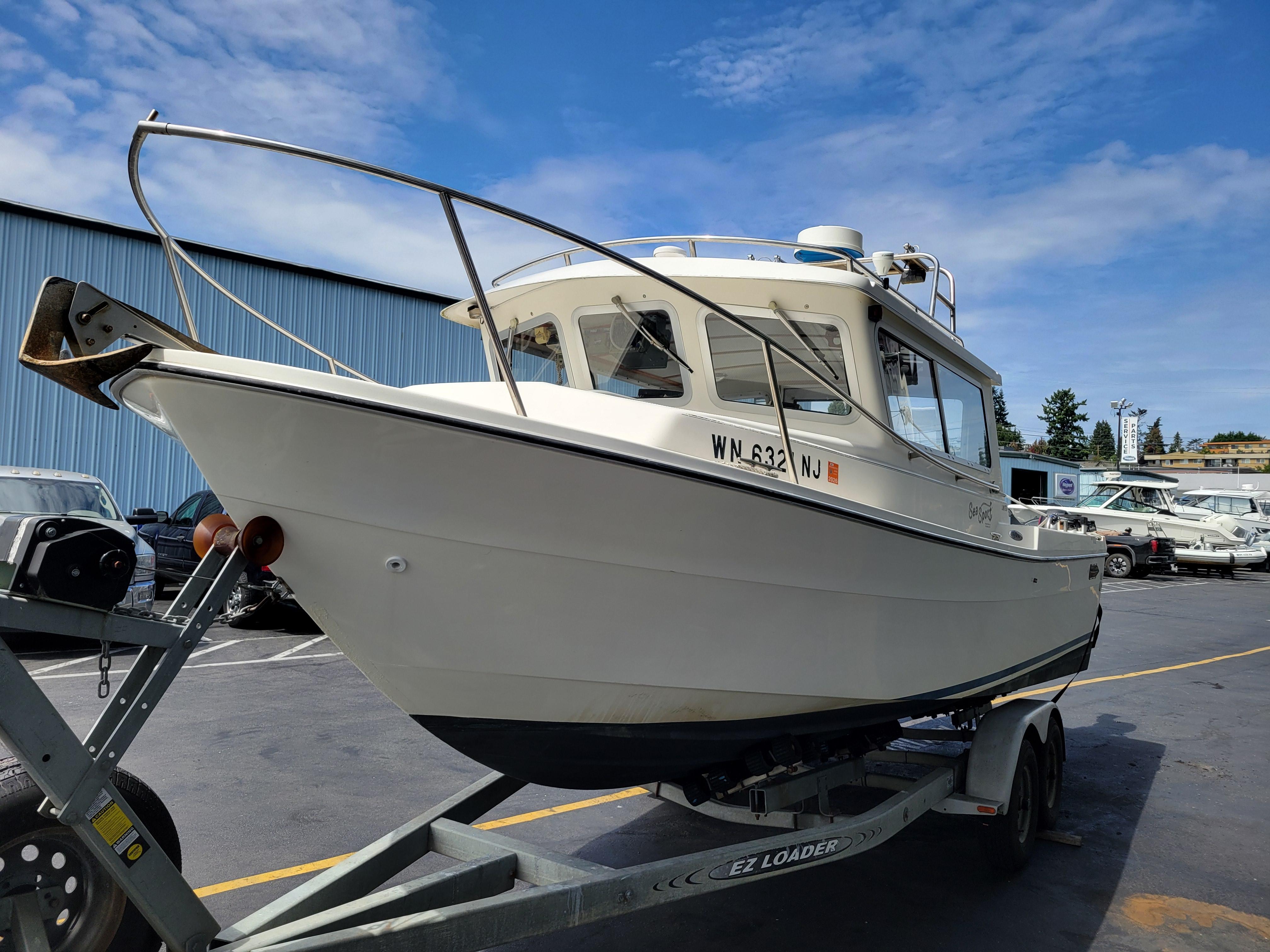 1999 SeaSport 2400 XL Limited boat on trailer, parked outdoors under blue sky.