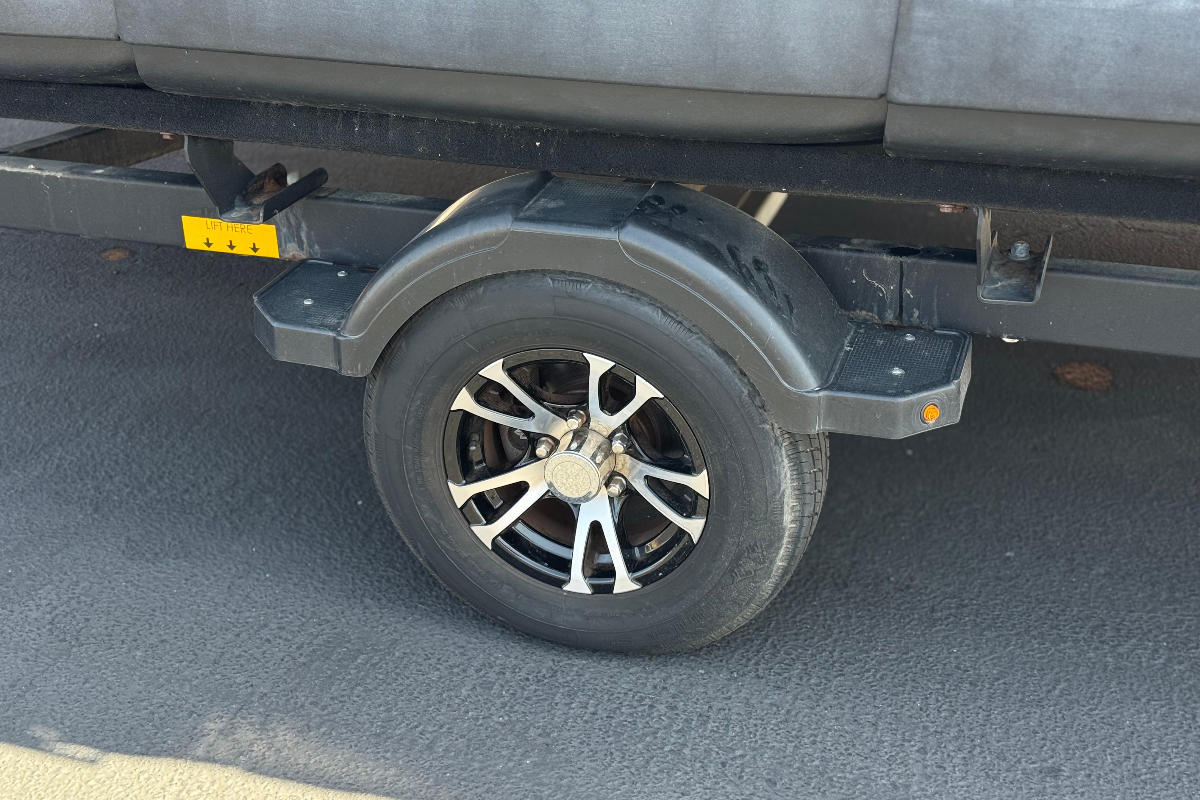 Trailer wheel of a 2022 Sea-Doo Switch Sport 18 on asphalt surface.