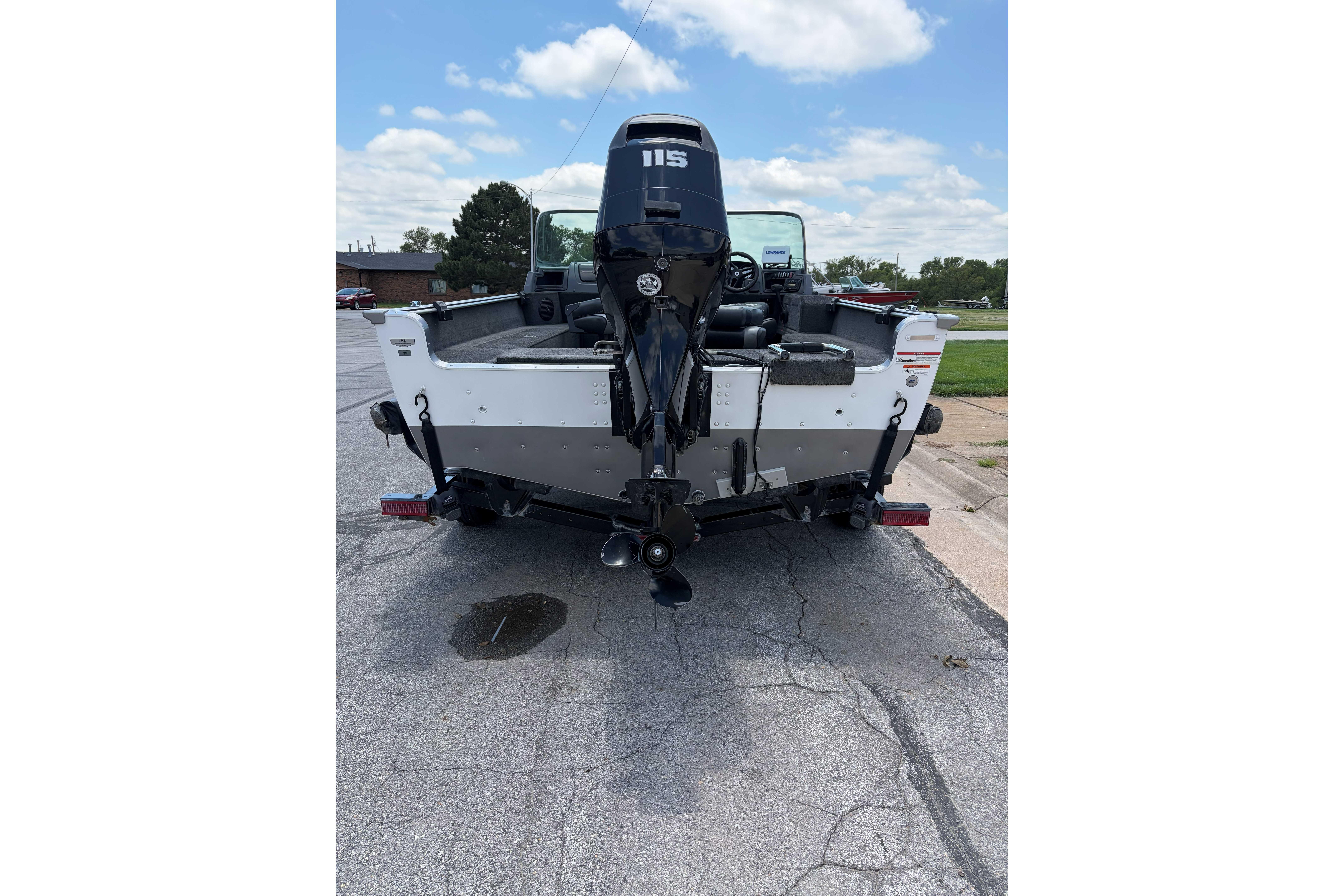2014 Lund 1875 Impact XS boat with 115 HP motor, parked on pavement.