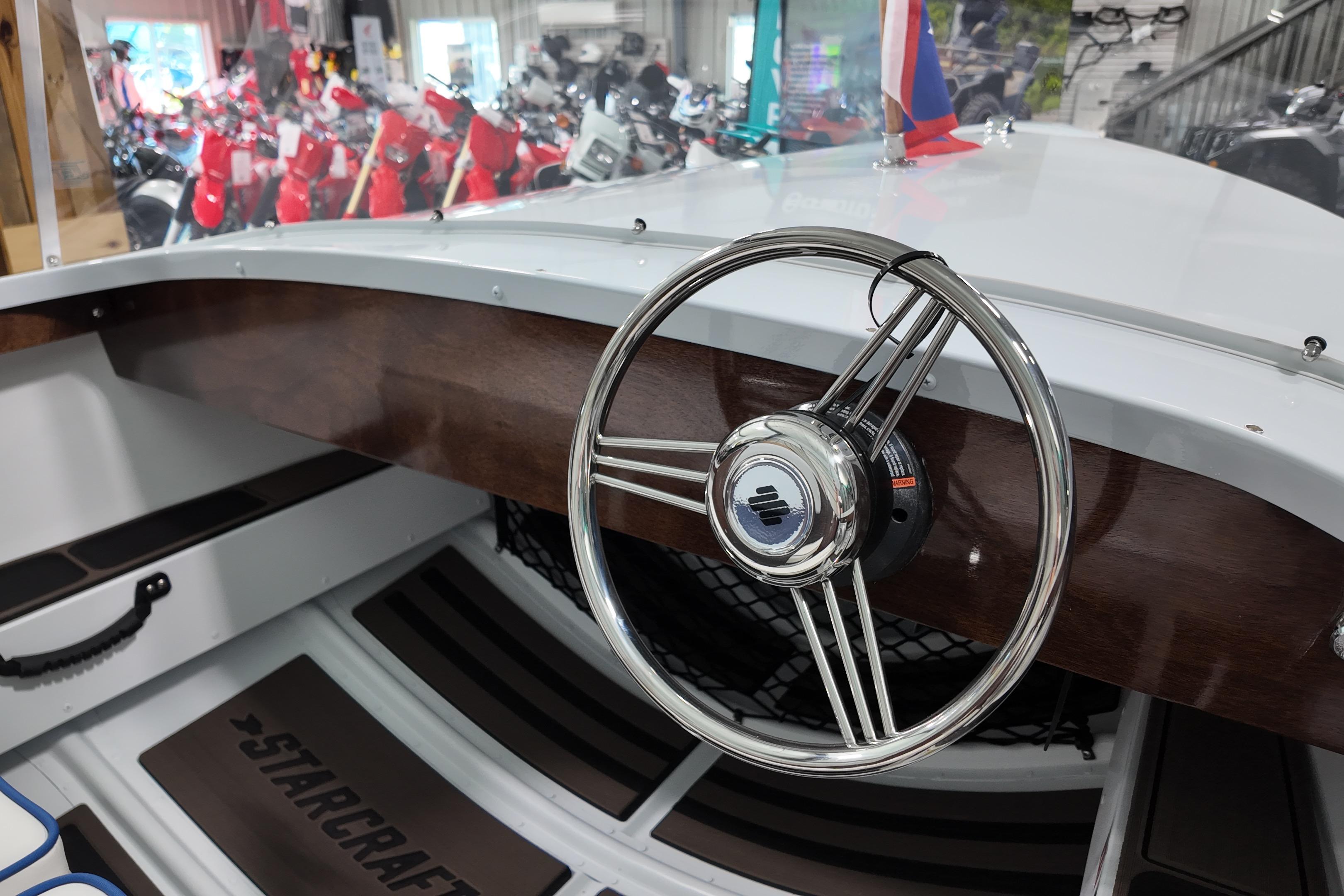 Steering wheel of 2026 Starcraft 57 Ski Champ boat, showcasing sleek design and craftsmanship.