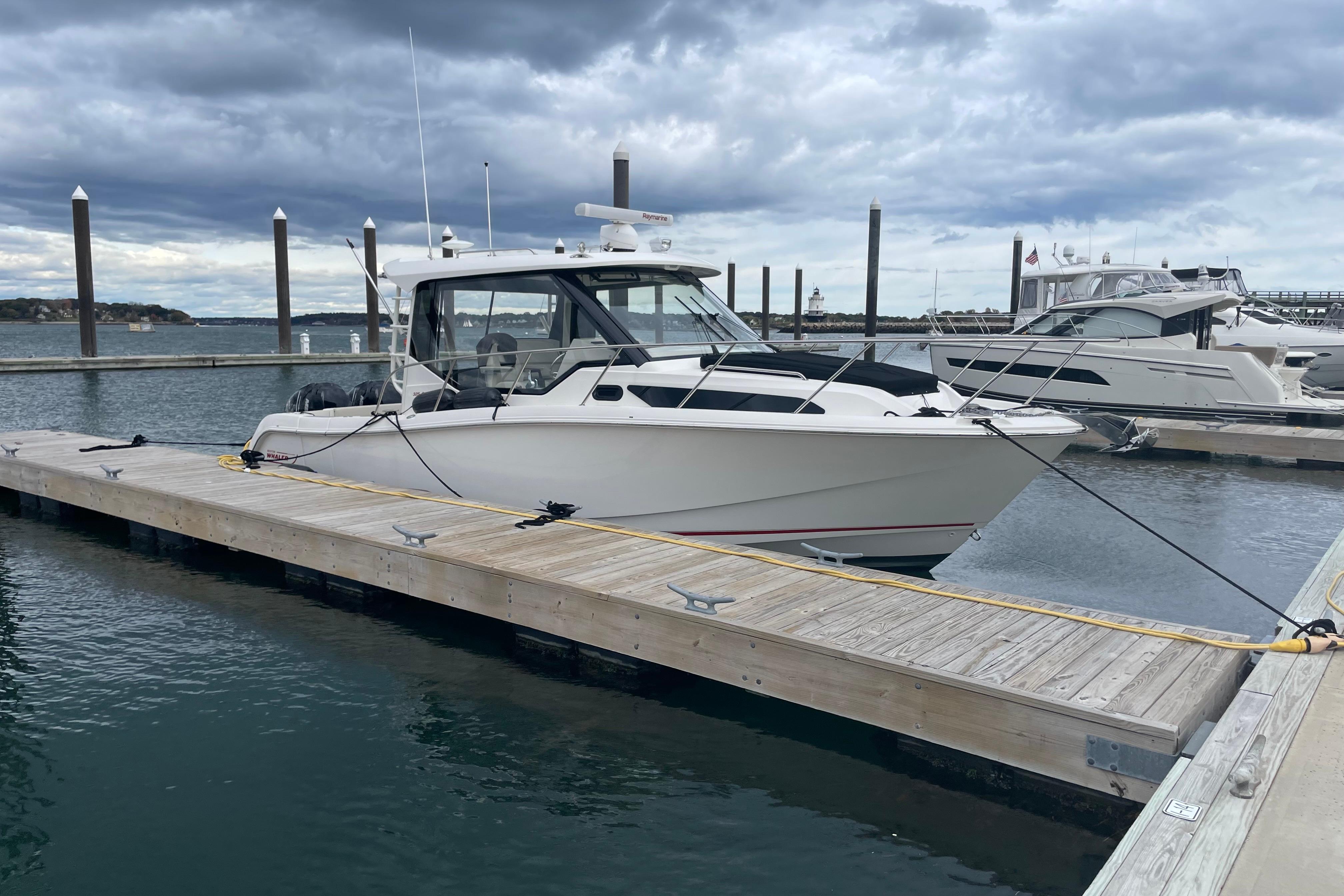 2023 Boston Whaler 325 Conquest docked at marina under cloudy sky.