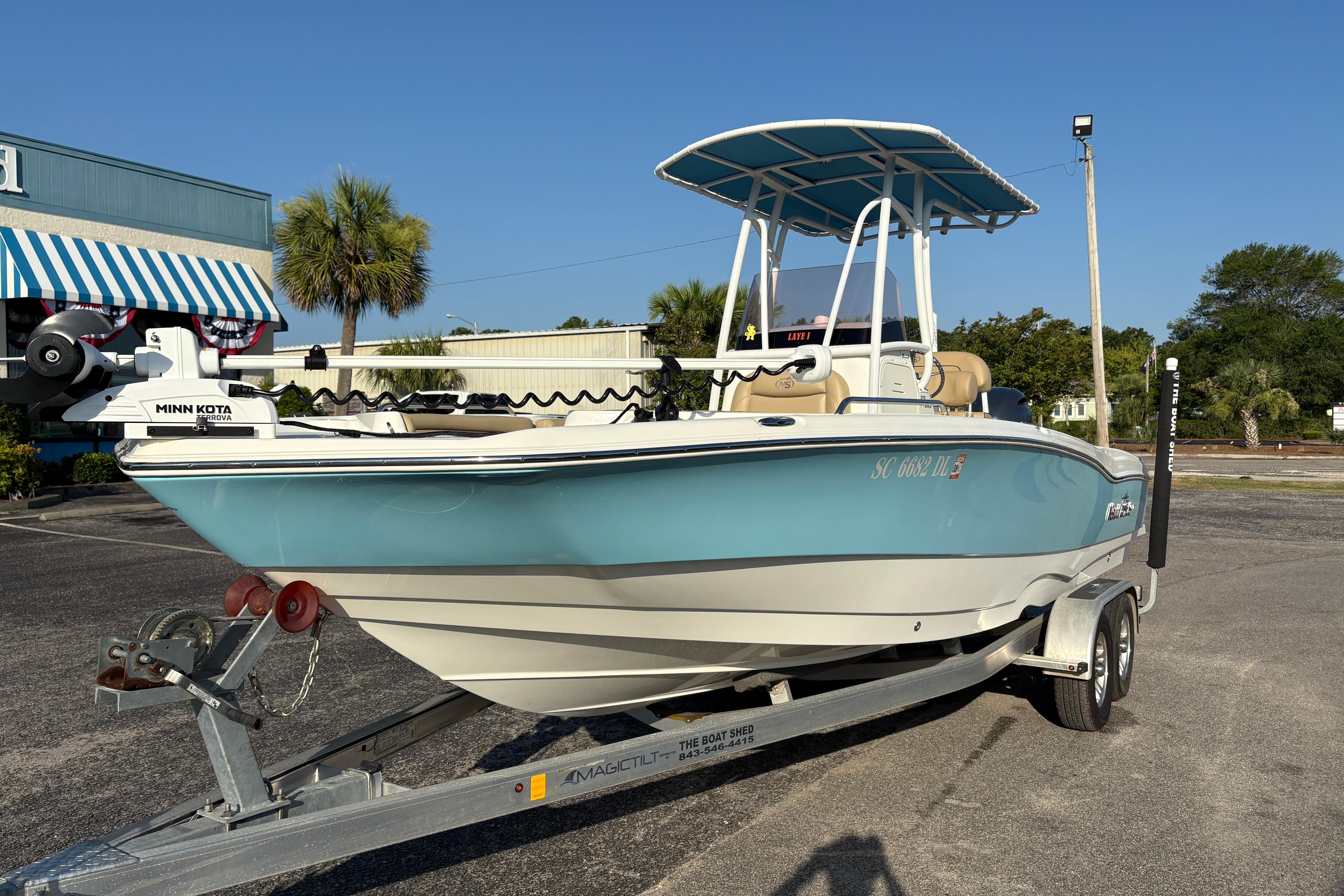 2019 NauticStar 231 Hybrid boat on trailer, featuring a blue hull and T-top canopy.