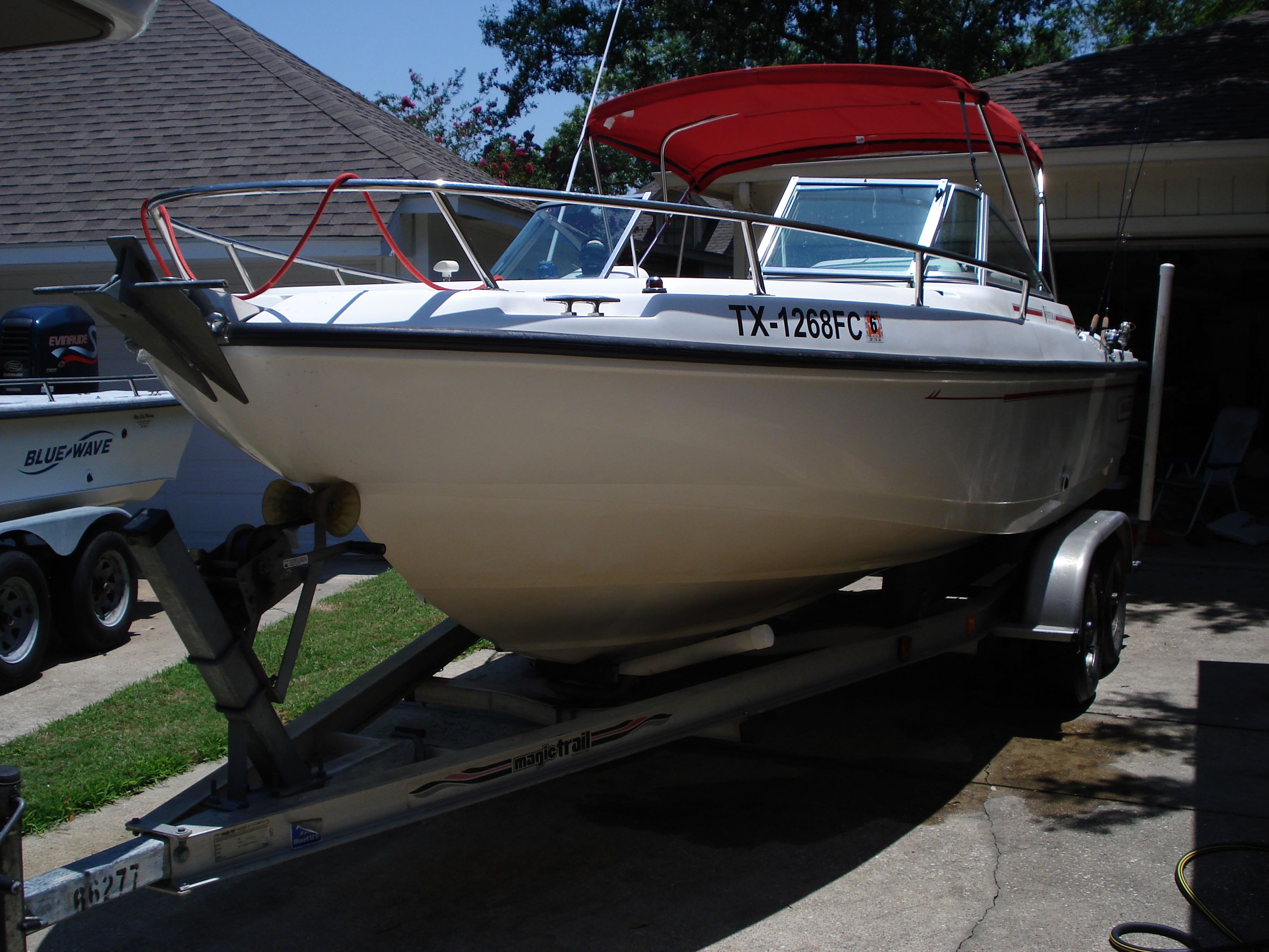 1998 Boston Whaler Ventura boat on trailer with red canopy, parked in driveway.