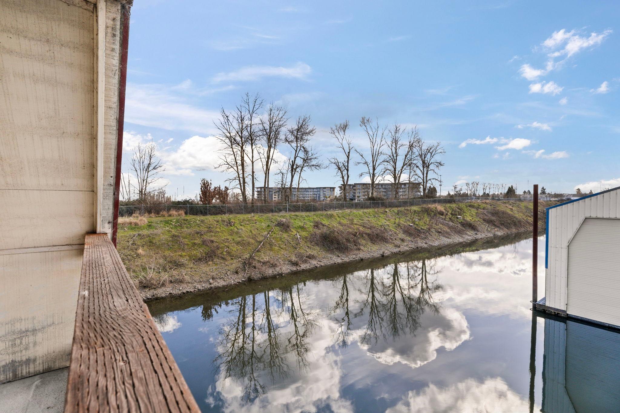 View from a 1976 Custom Boathouse overlooking a serene river with tree reflections.
