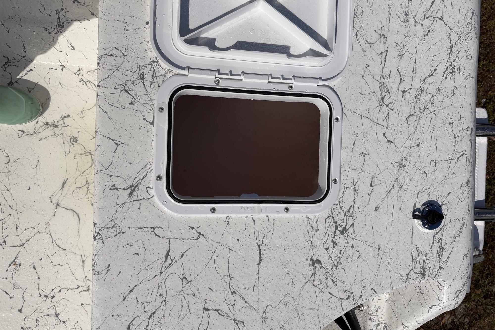 Open hatch on 2027 Coastal Skiff 184 boat with marbled deck design.
