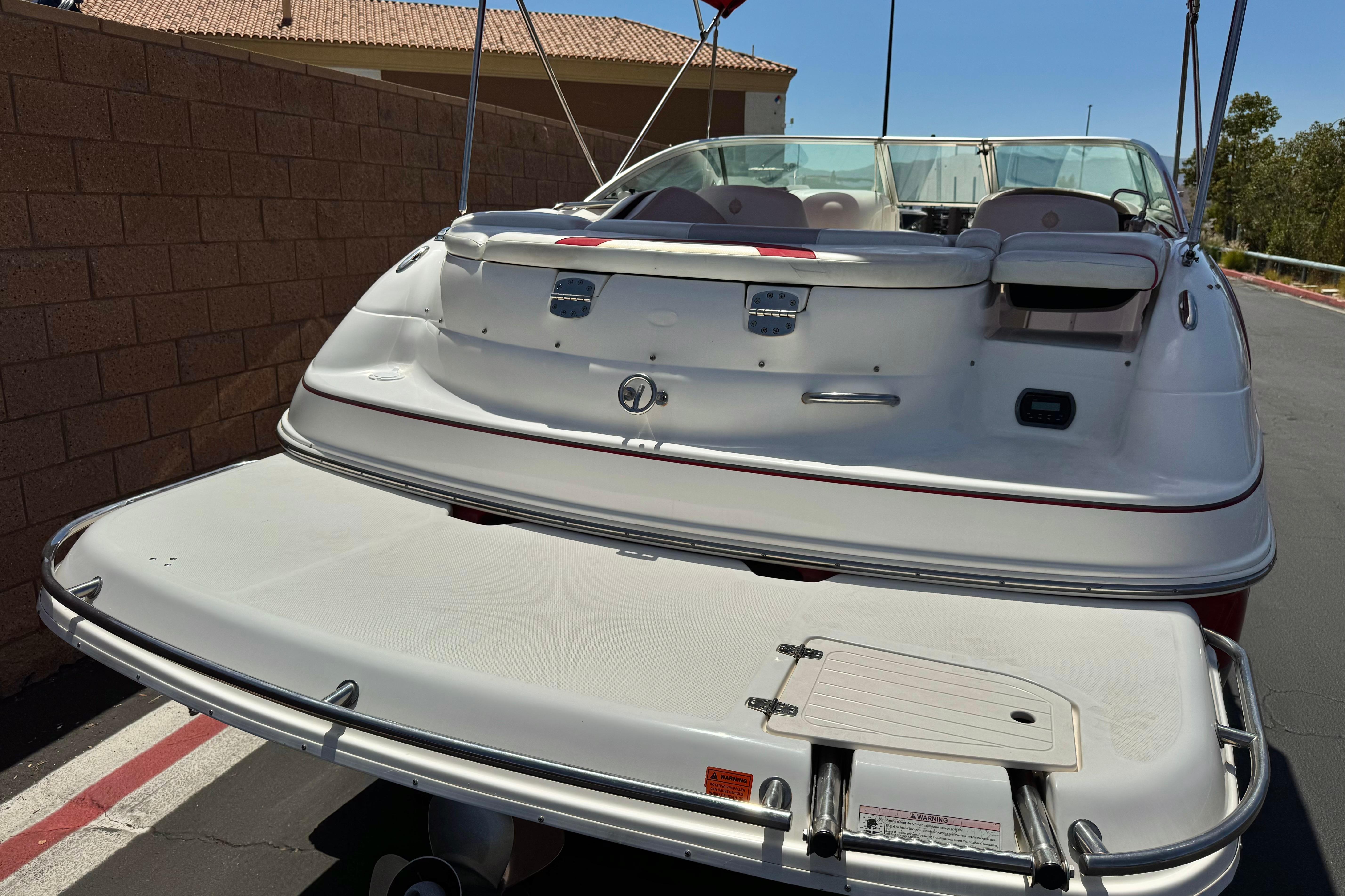 2010 Bryant 255 boat with swim platform, parked near a brick wall.