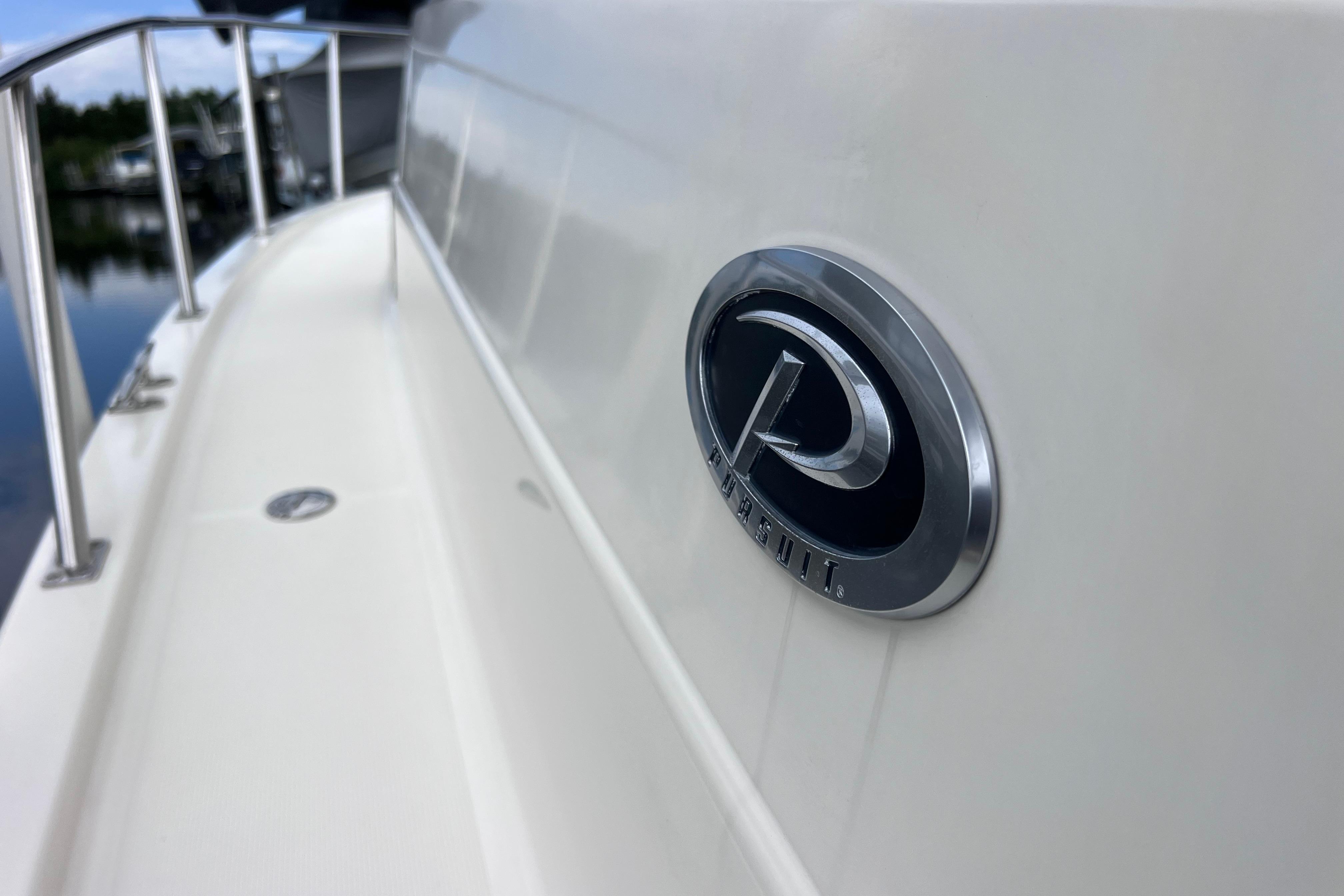 2005 Pursuit 3070 Offshore boat with logo, railing, and water reflection.