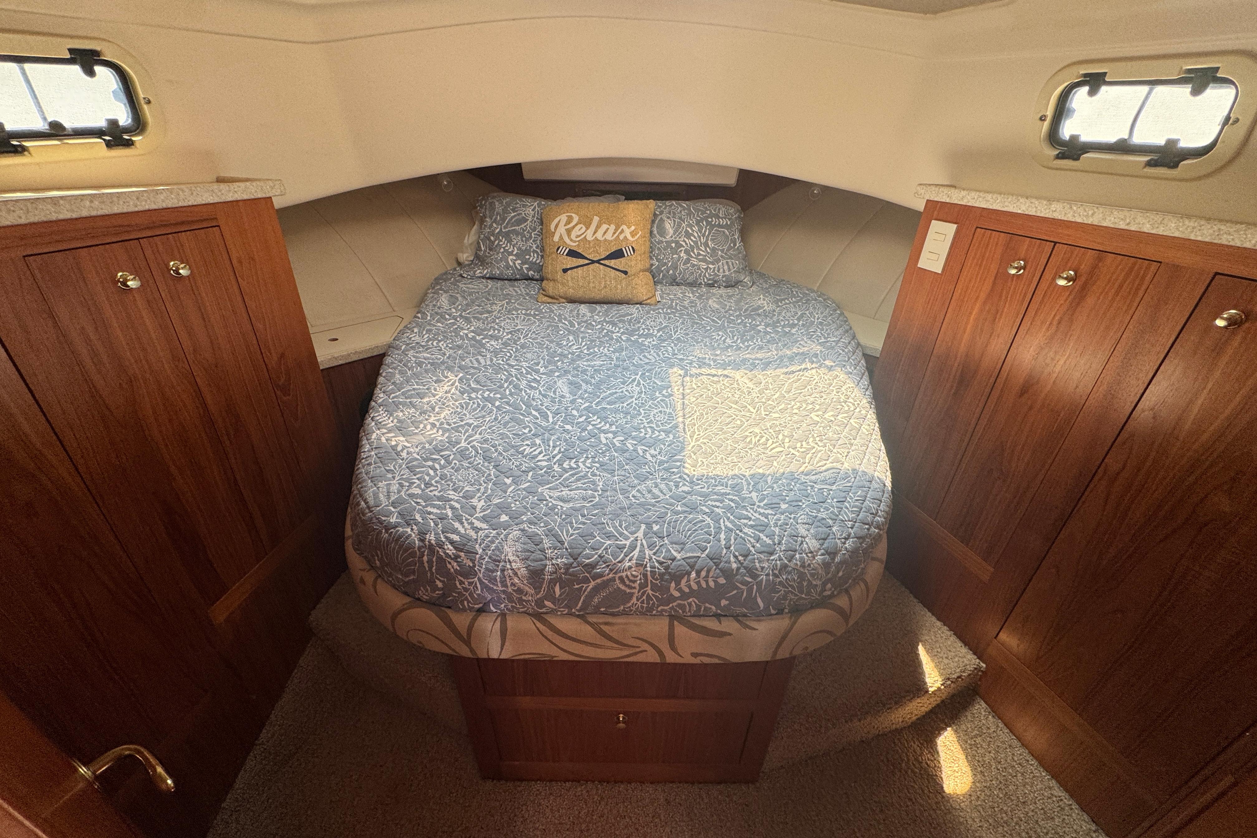 Cozy cabin interior of 2002 Mainship 390 Trawler with wood cabinets and a comfortable bed.