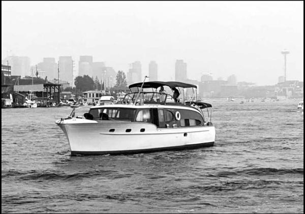 1951 Chris-Craft Catalina boat cruising on water with city skyline in background.
