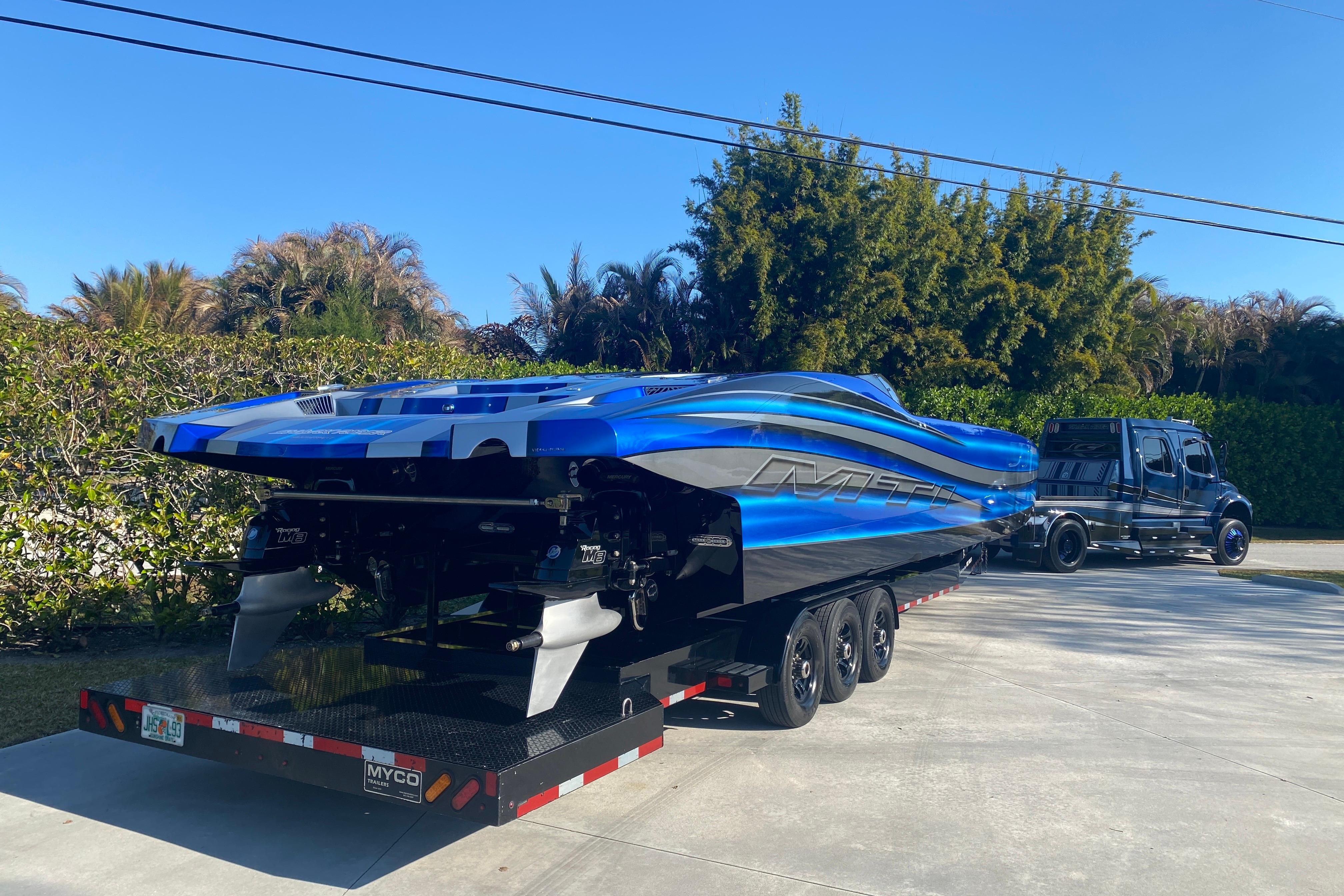 2016 MTI 44 RP powerboat on trailer, vibrant blue design, parked outdoors.