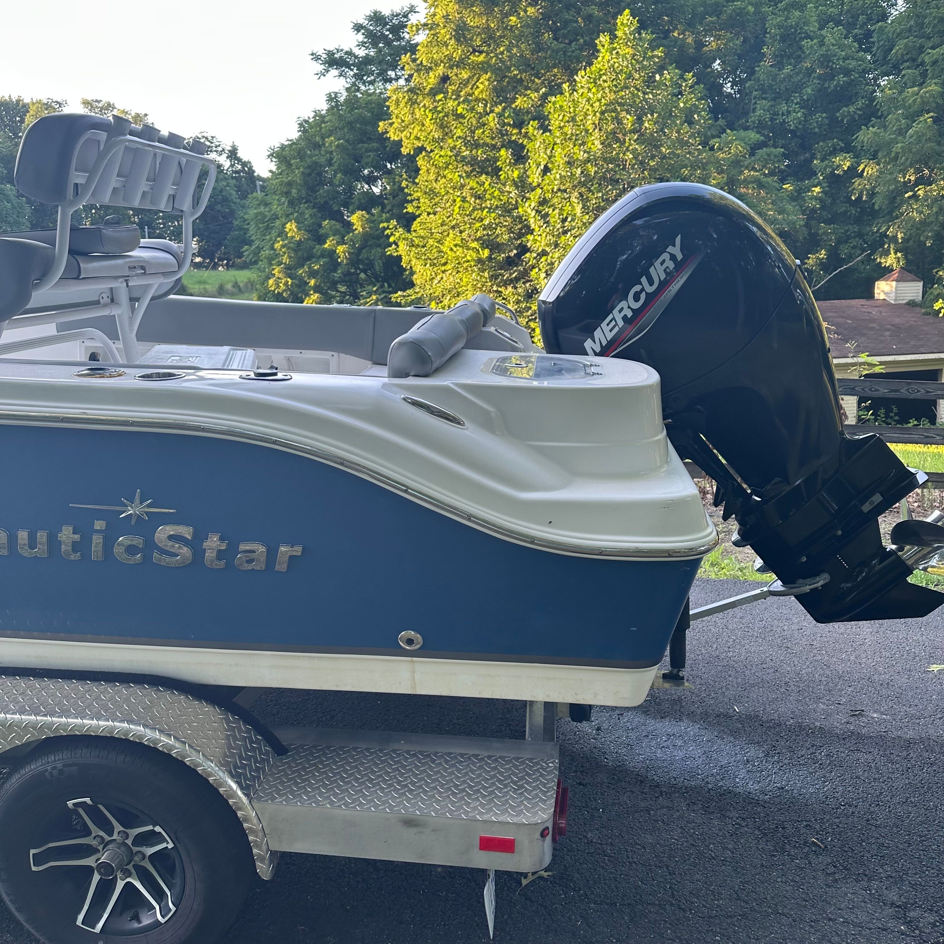 A blue and white 2022 NauticStar 2102 Legacy on a trailer, featuring a Mercury outboard motor.