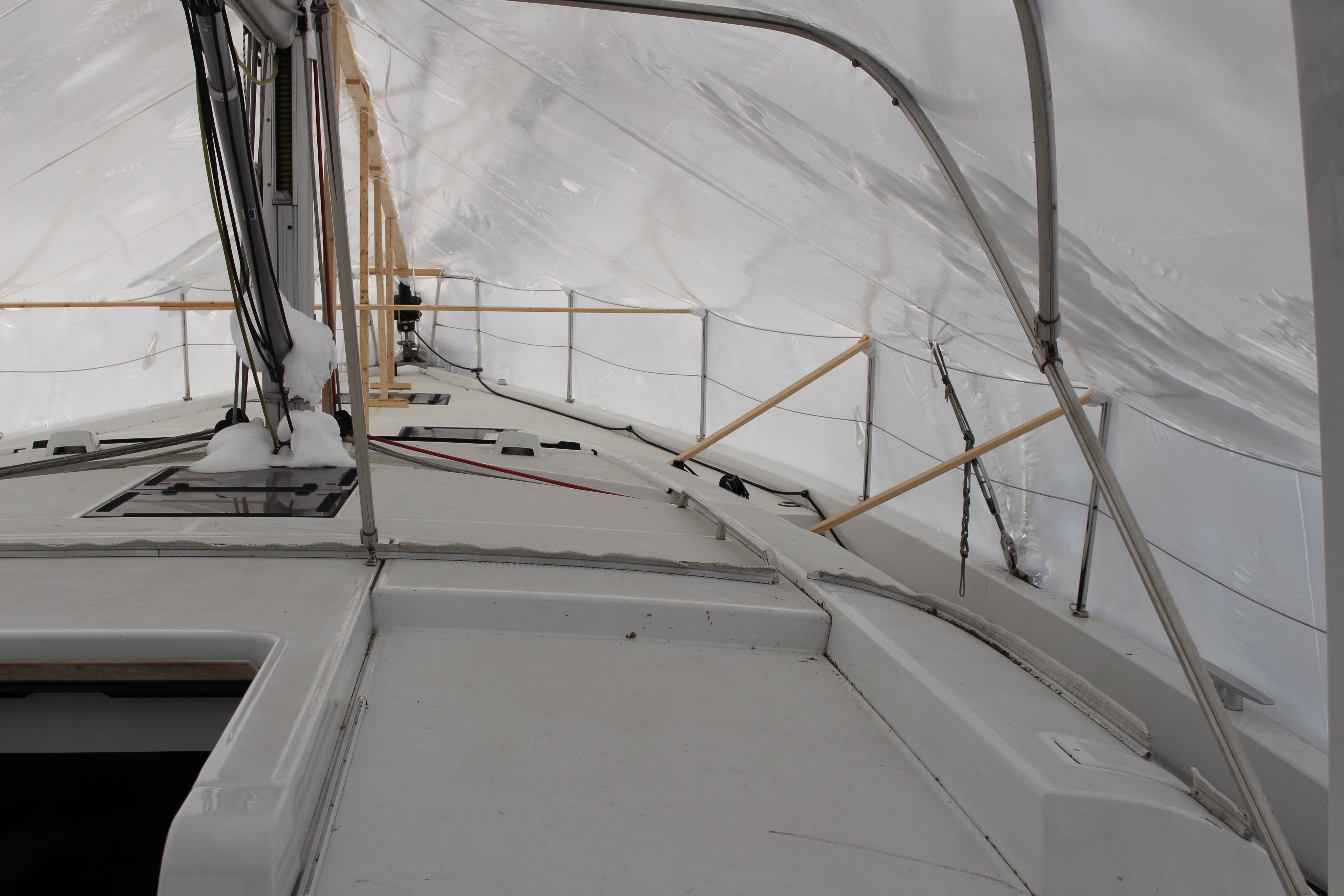 Looking port and forward: Beneteau Oceanis Yacht 54, 2022 model, covered in snow under protective shelter.