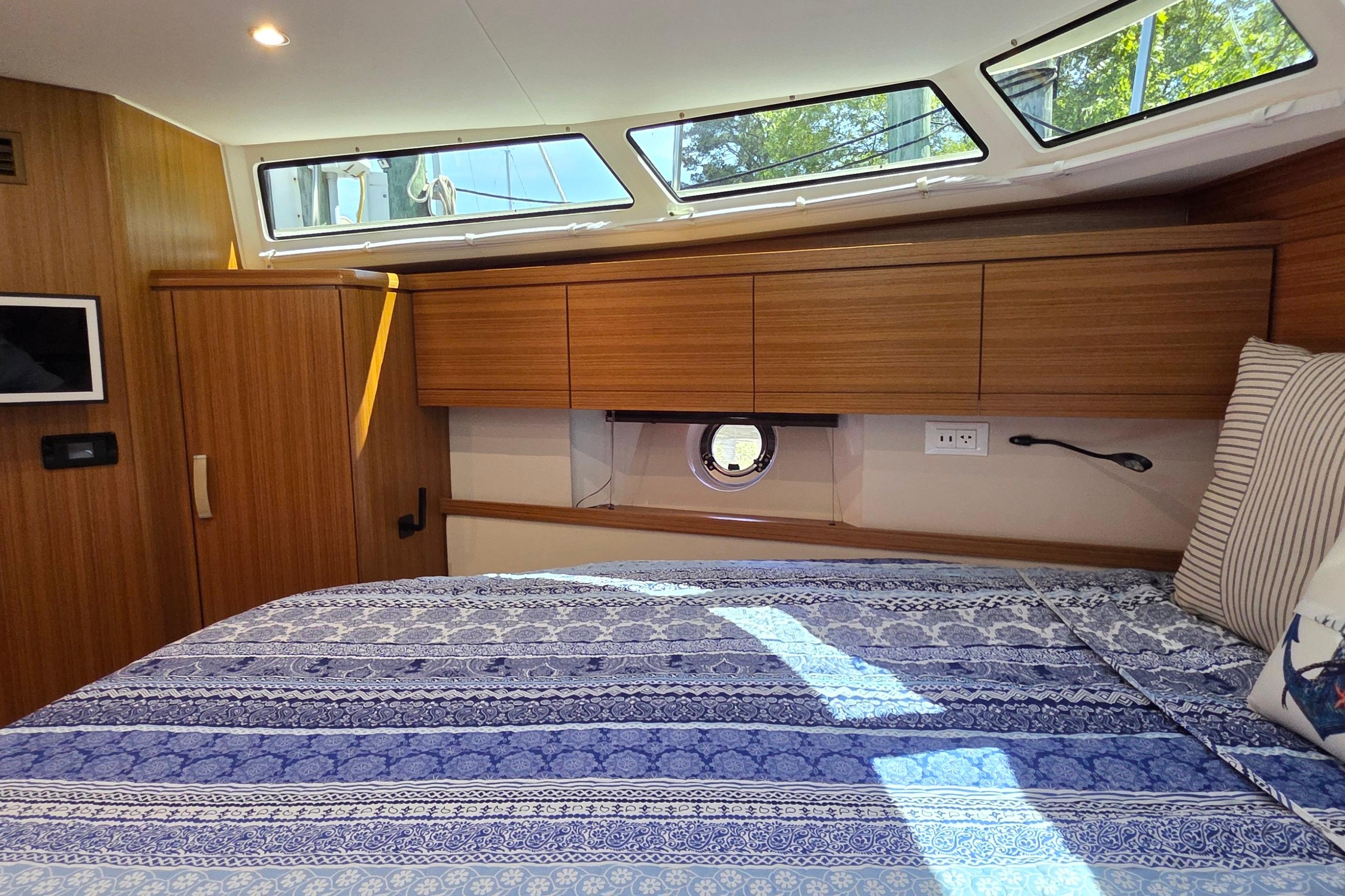 Luxurious cabin interior of 2023 Greenline 40 yacht with wood finish and patterned bedding.