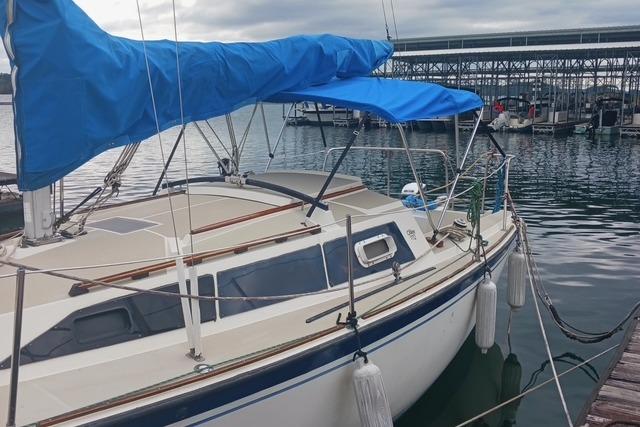 1989 O'Day 272 sailboat docked with blue sail cover, marina background.