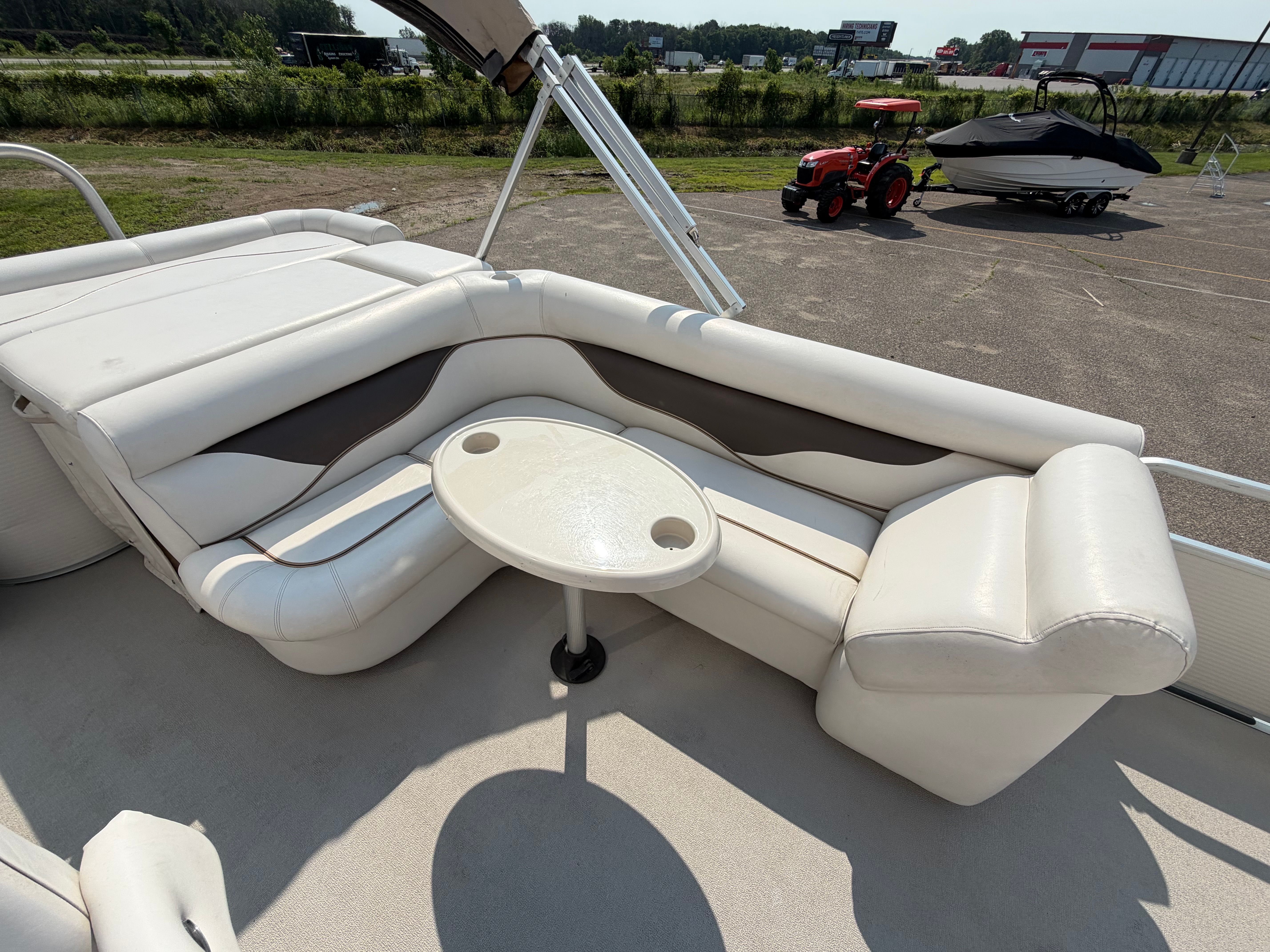 The image shows the interior of a Premier 225 Sunsation pontoon boat with white seating and a table.