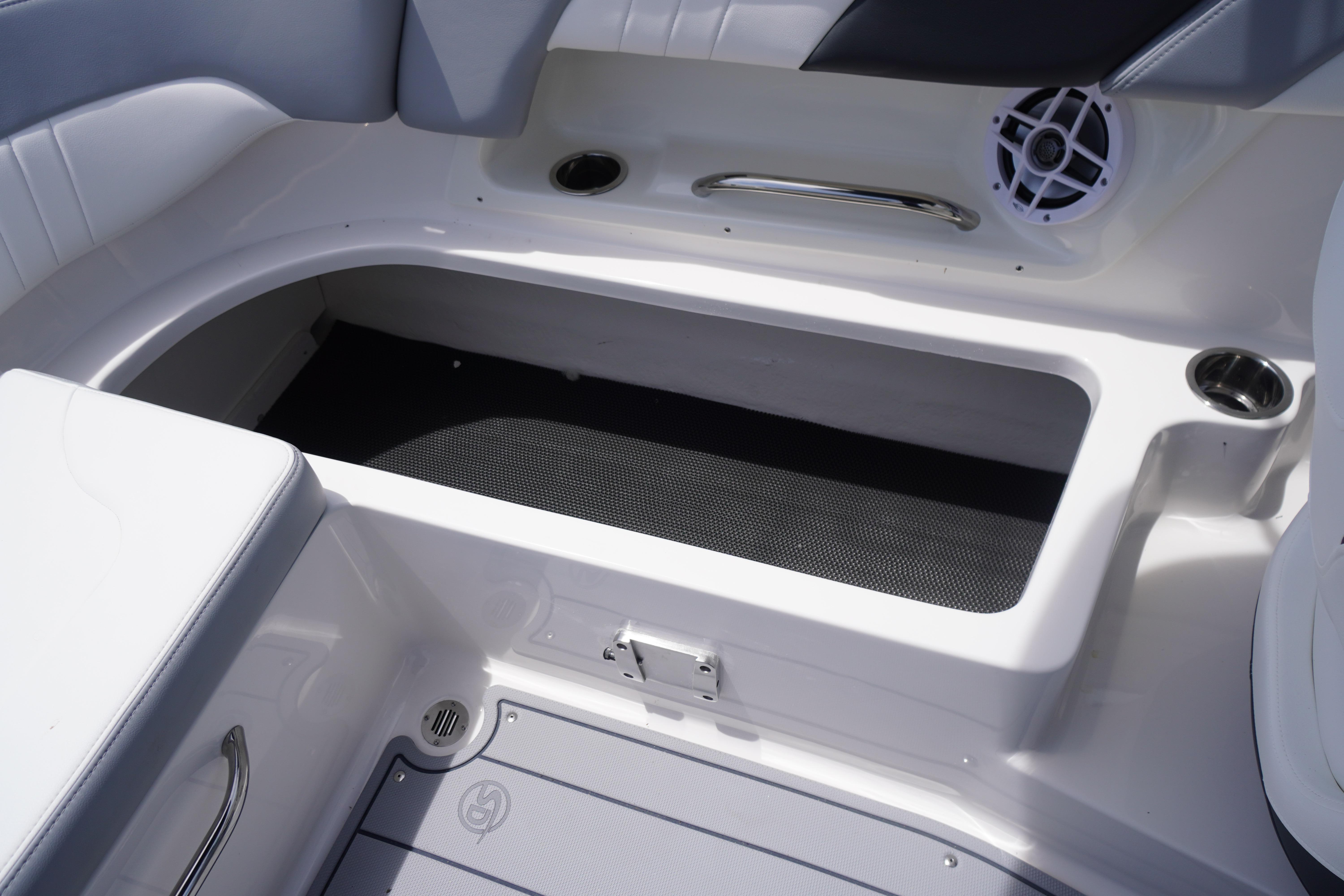 2026 Chaparral 23 SSi OB boat interior storage compartment with speaker and cup holder.