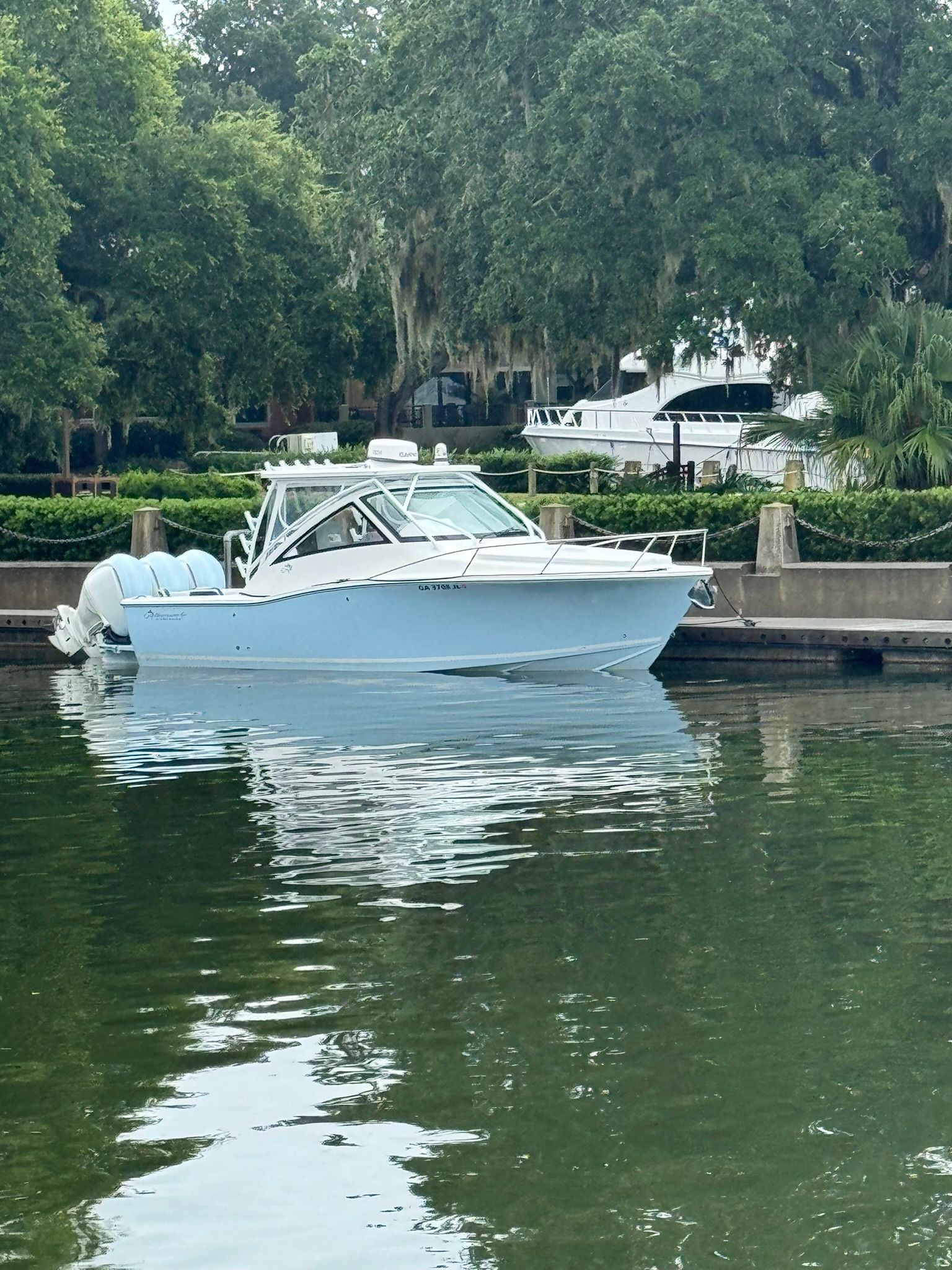 A 2024 Albemarle 30 Express boat sits calmly on the water, surrounded by green trees.