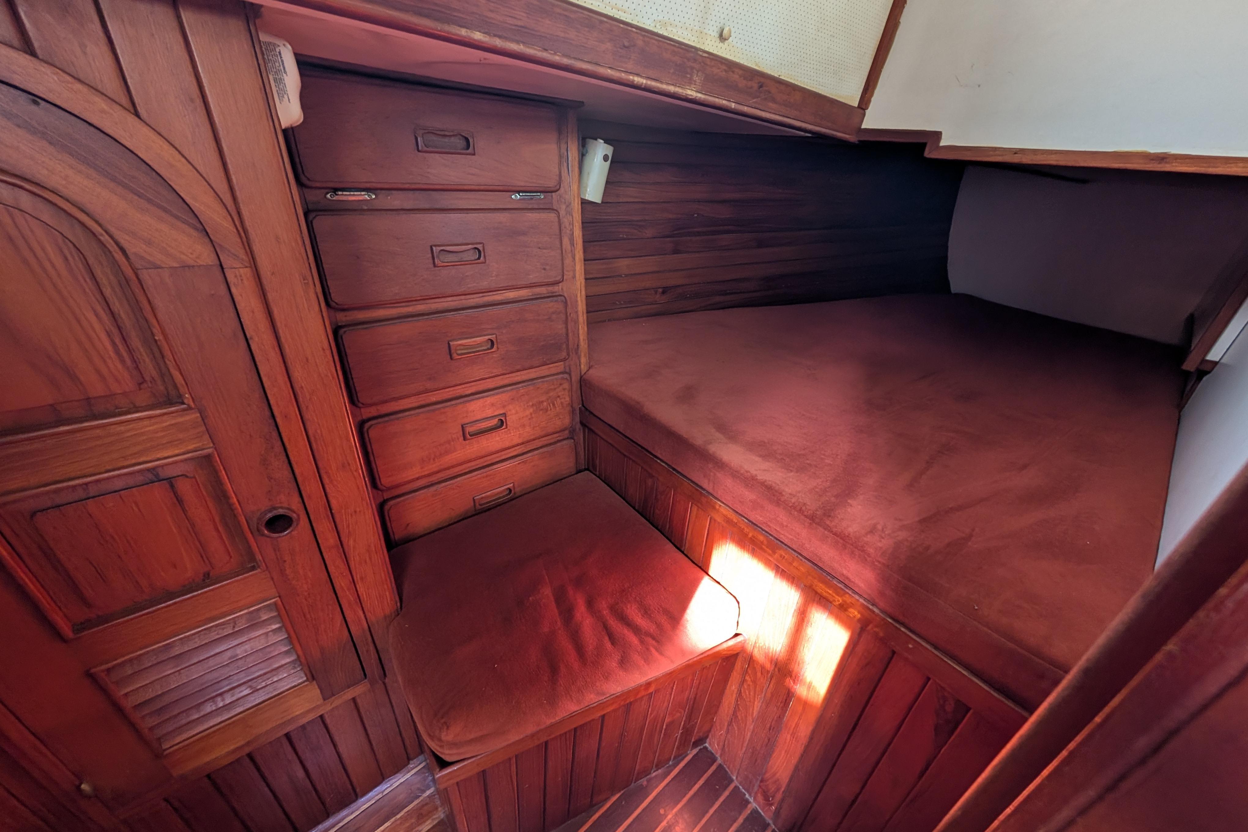 Cozy wooden cabin interior of 1983 Robert Perry 41 sailboat with built-in storage.