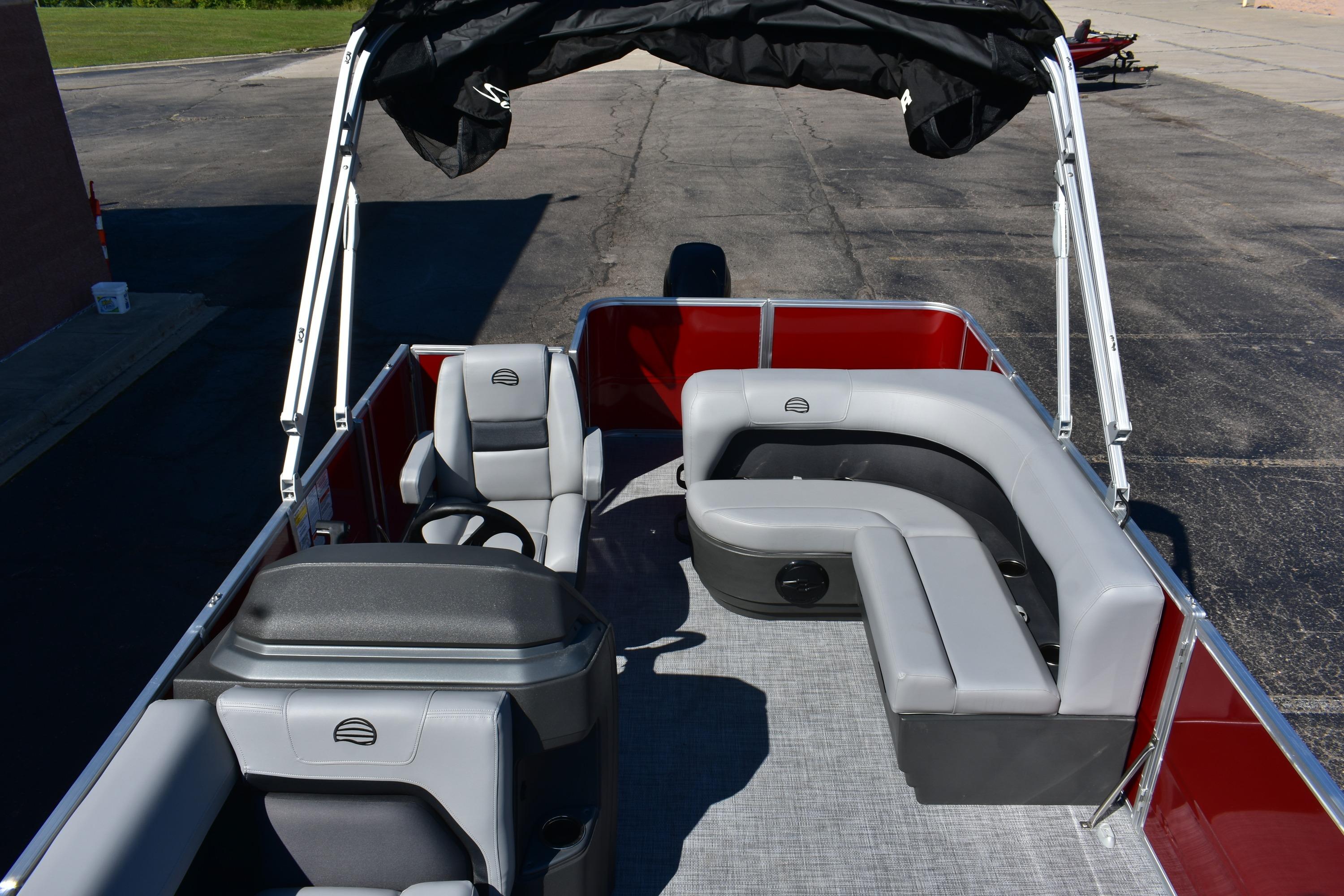 2026 Sun Tracker Party Barge 18 DLX with gray seating and canopy, docked on pavement.